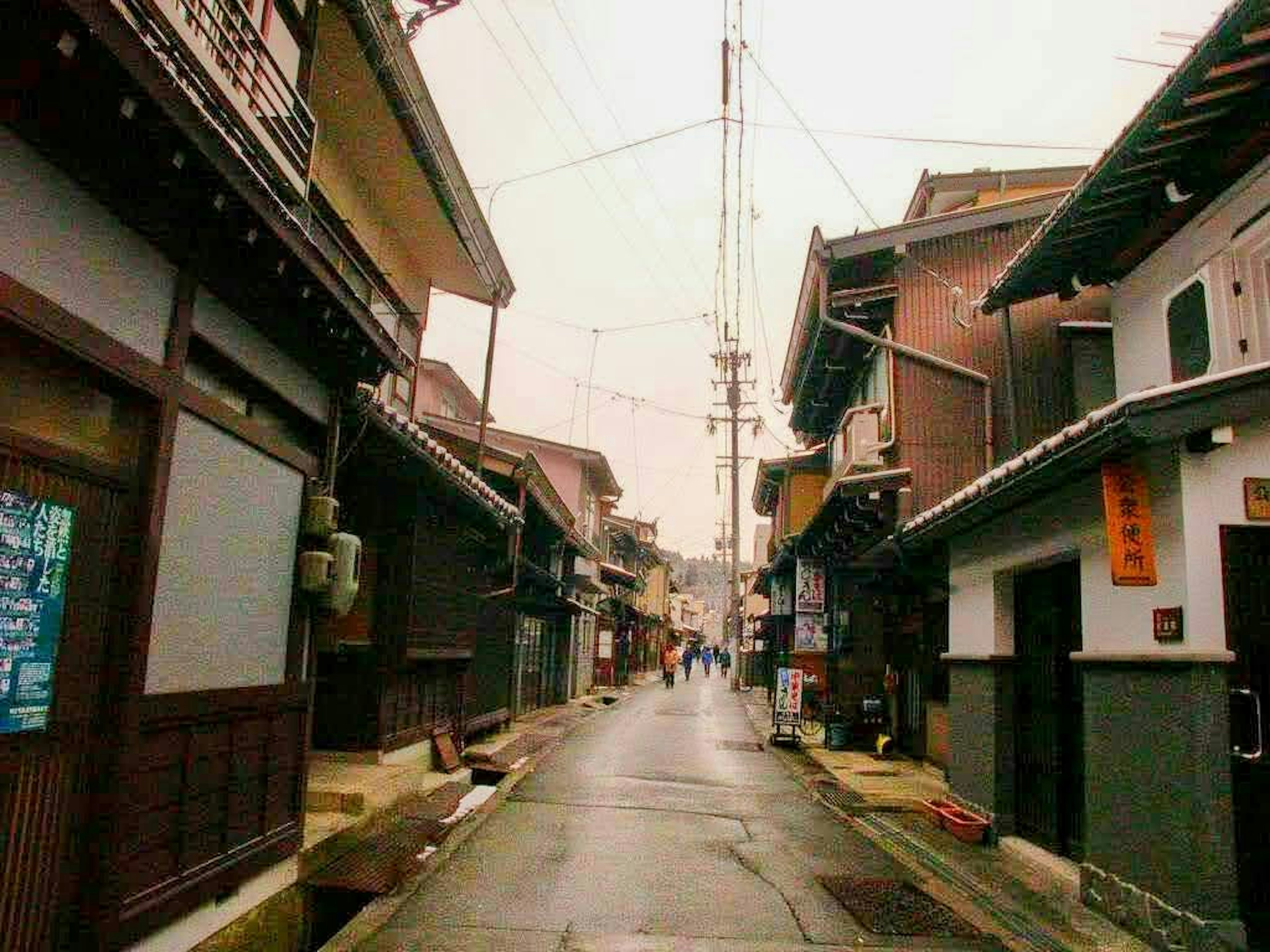 静かな日本の街並み、雨の中の古い木造の家々、濡れた路面、電線が交差する風景