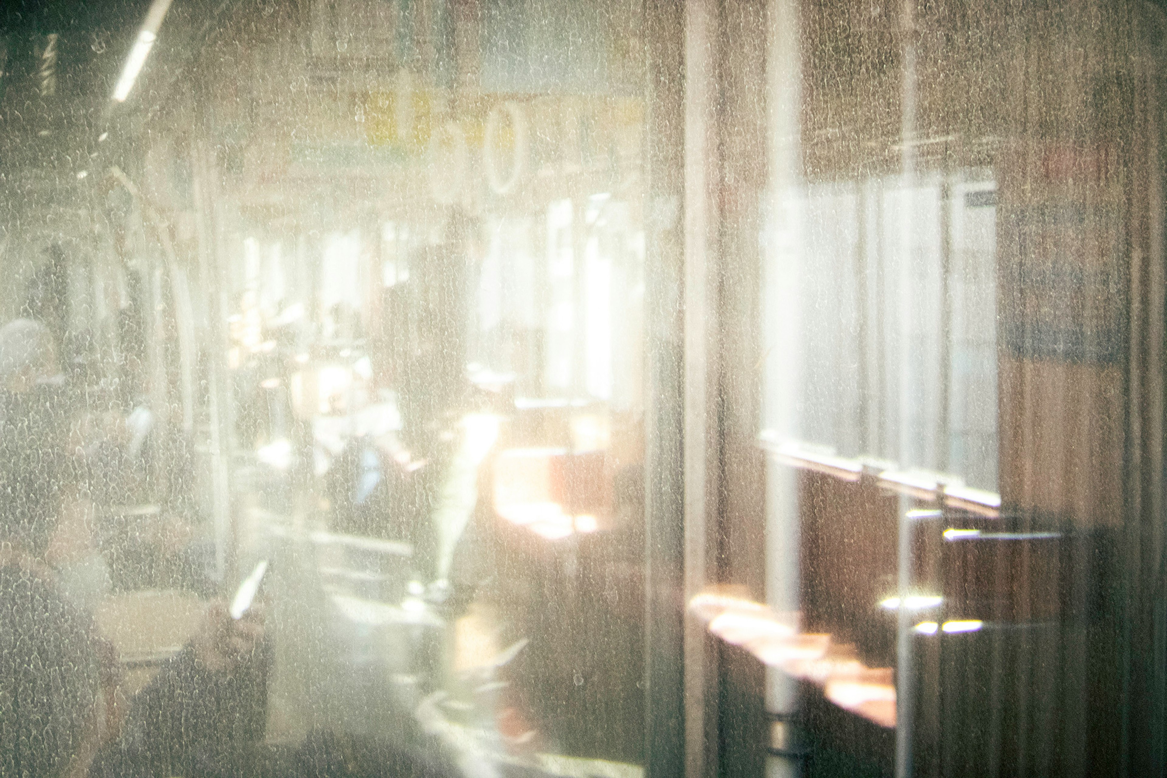 Vista borrosa a través de una ventana que muestra pasajeros y reflejos de luz