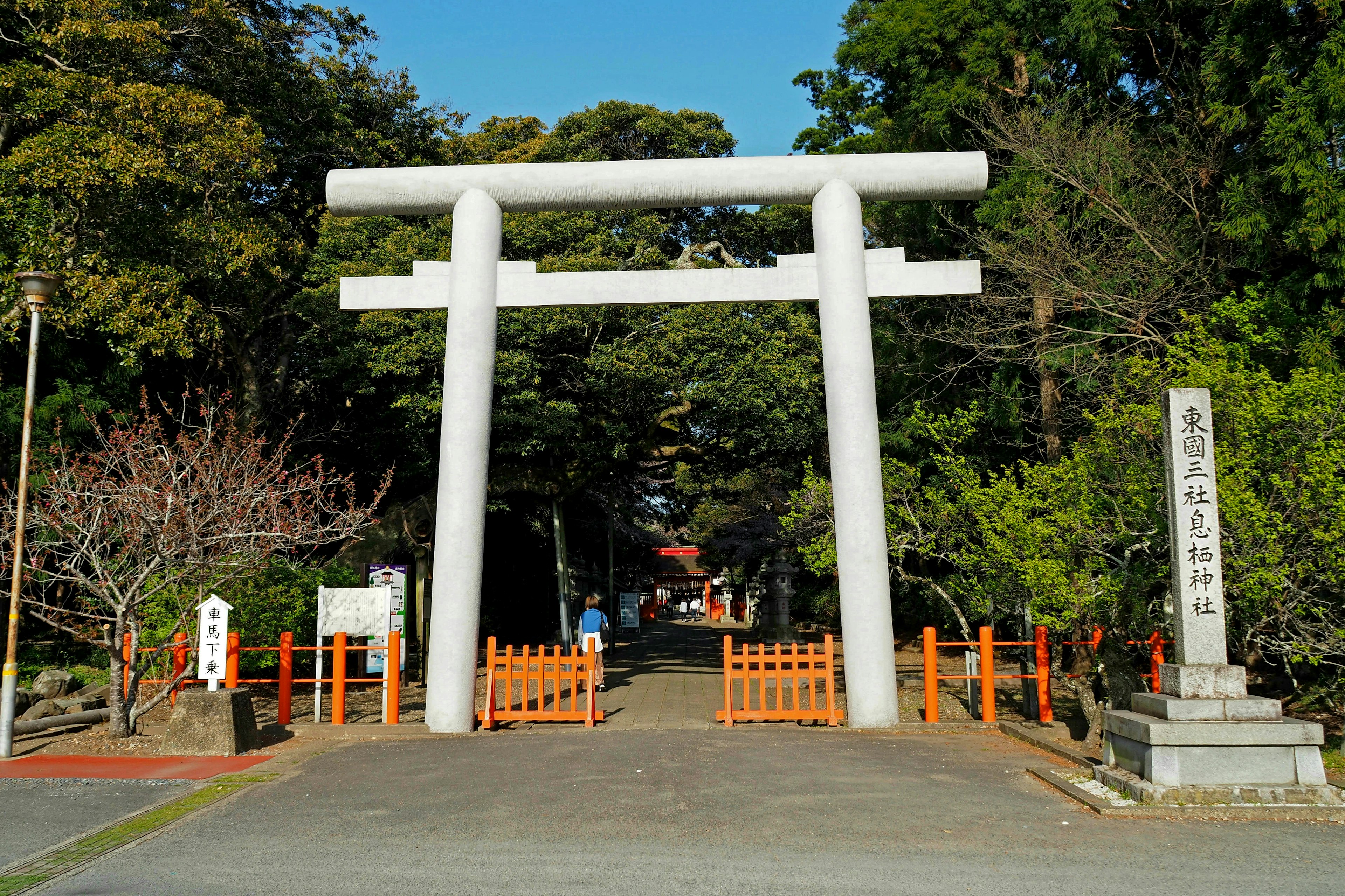 Entrance of a shrine featuring a white torii gate and orange fence