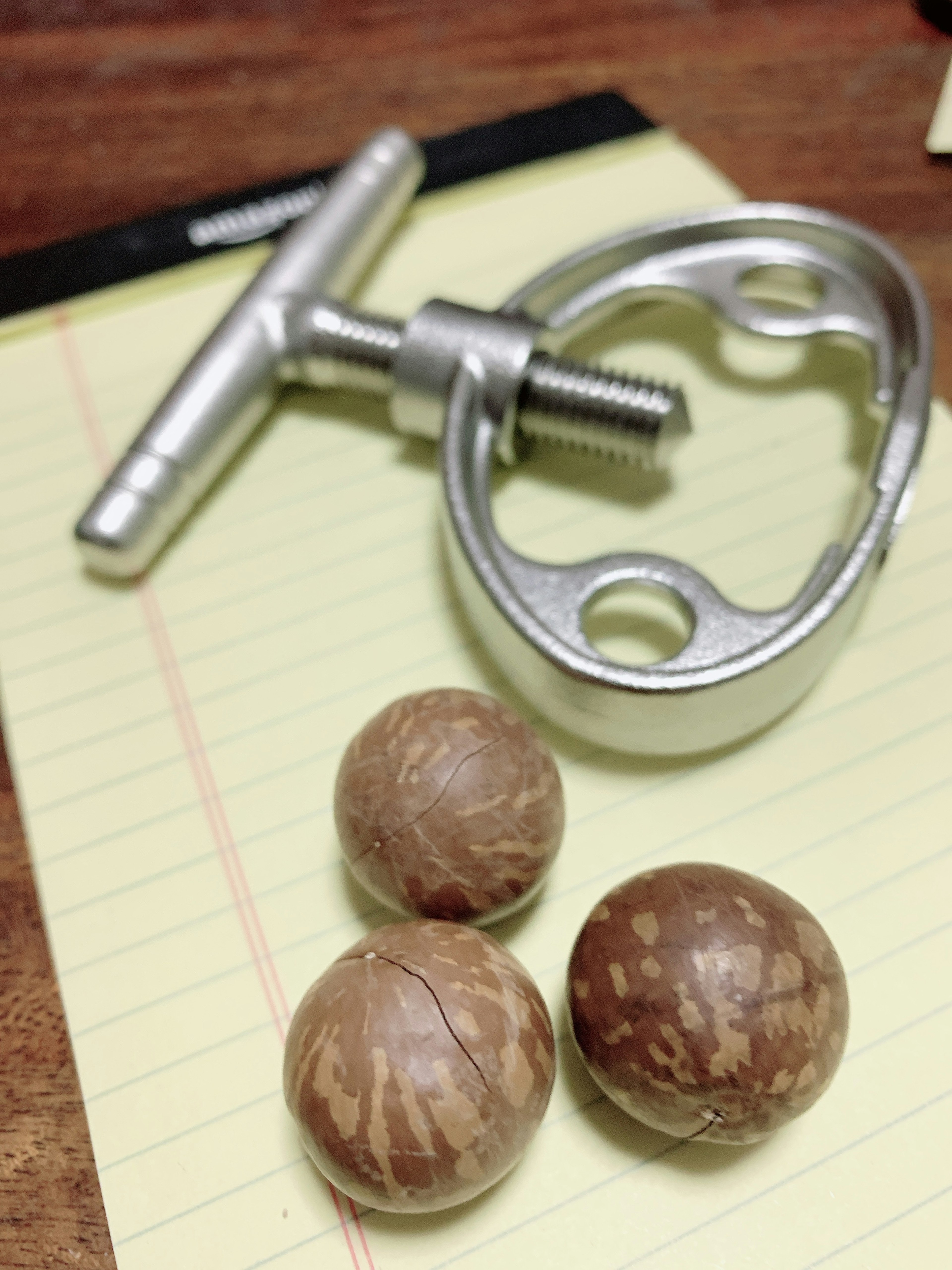 Three nut-like balls and a metallic tool on a notepad