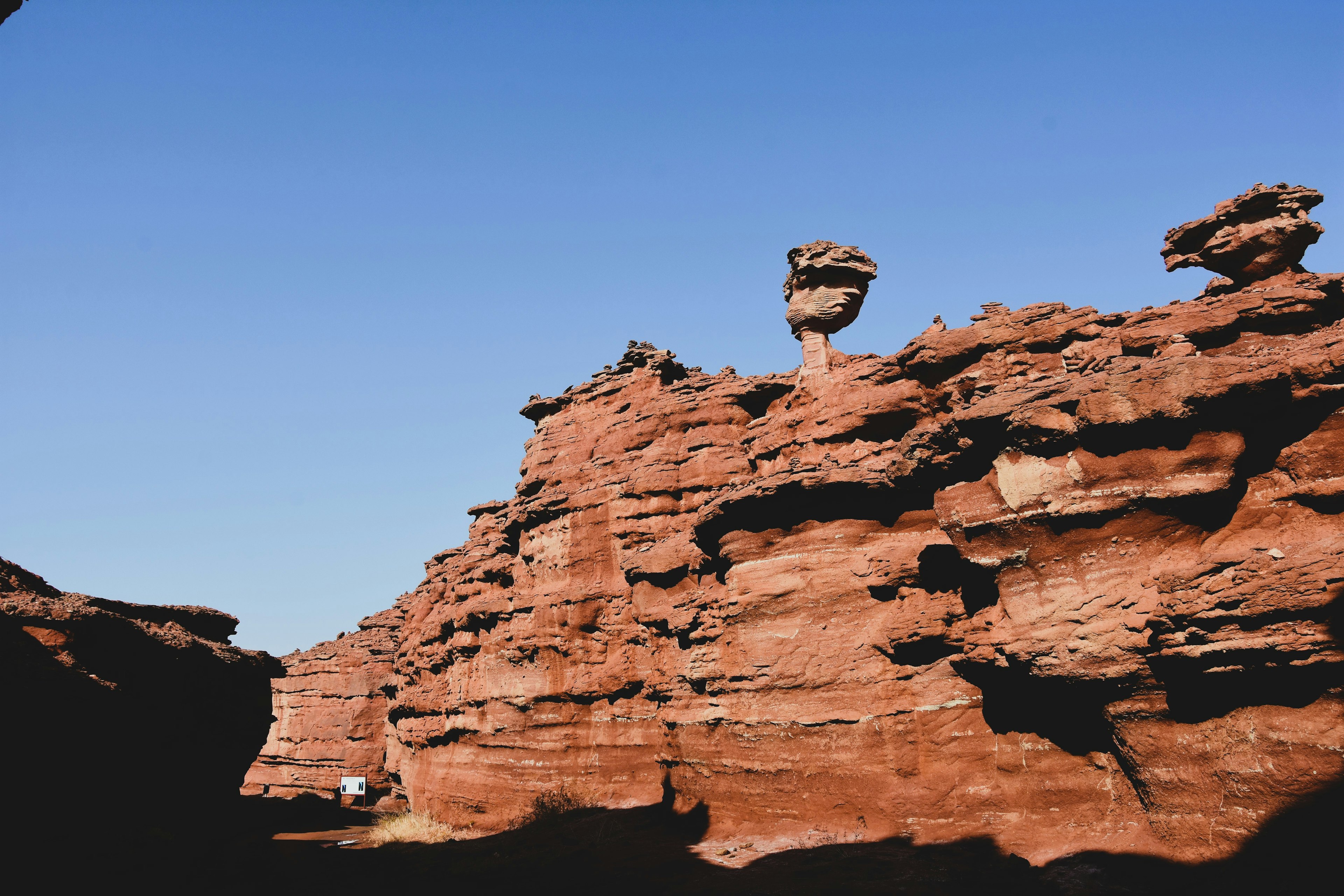 Paesaggio di rocce rosse con una formazione rocciosa distintiva contro un cielo blu