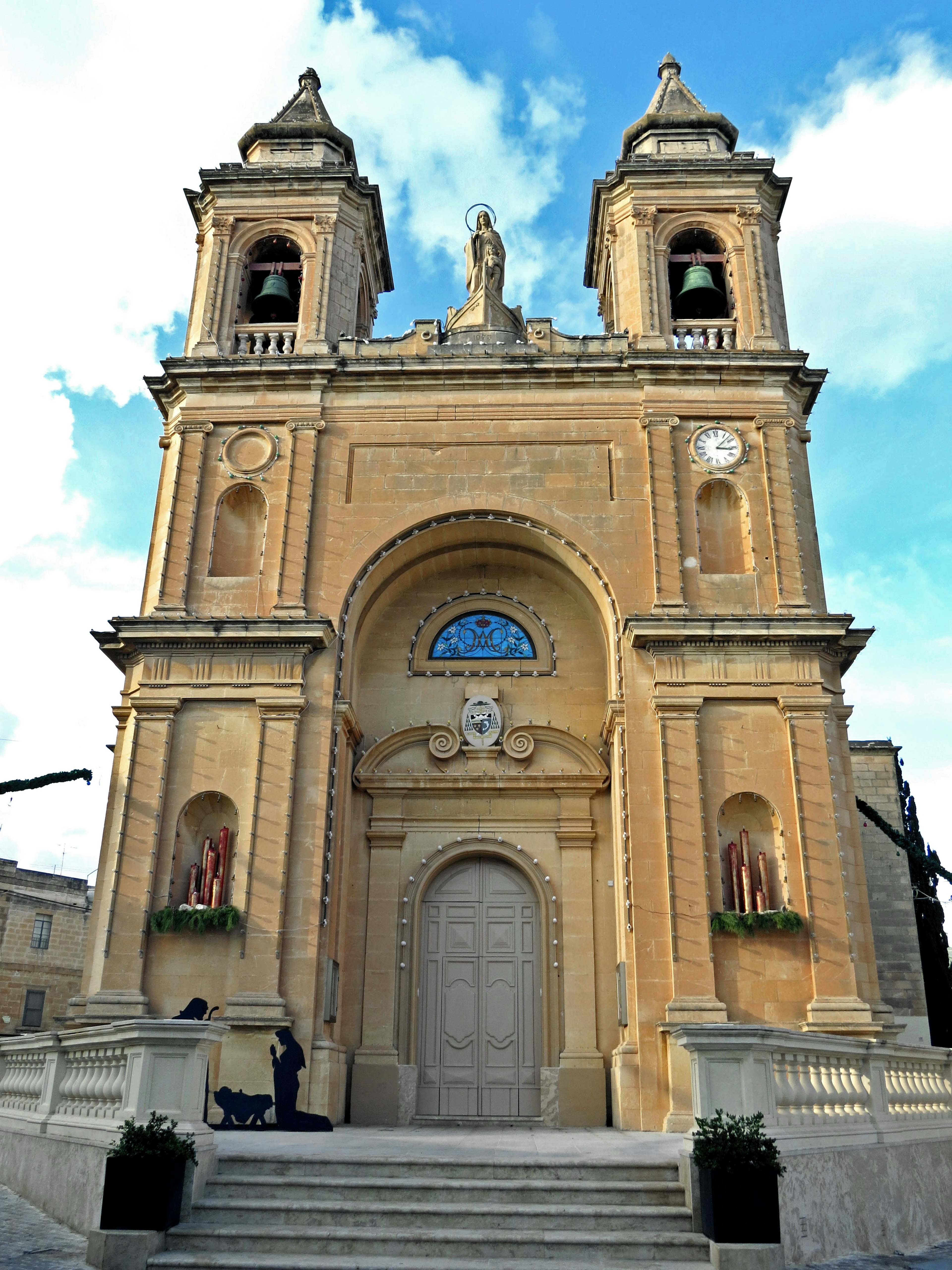 Facciata di chiesa bellissima in pietra dorata, sotto un cielo blu, con sculture intricate