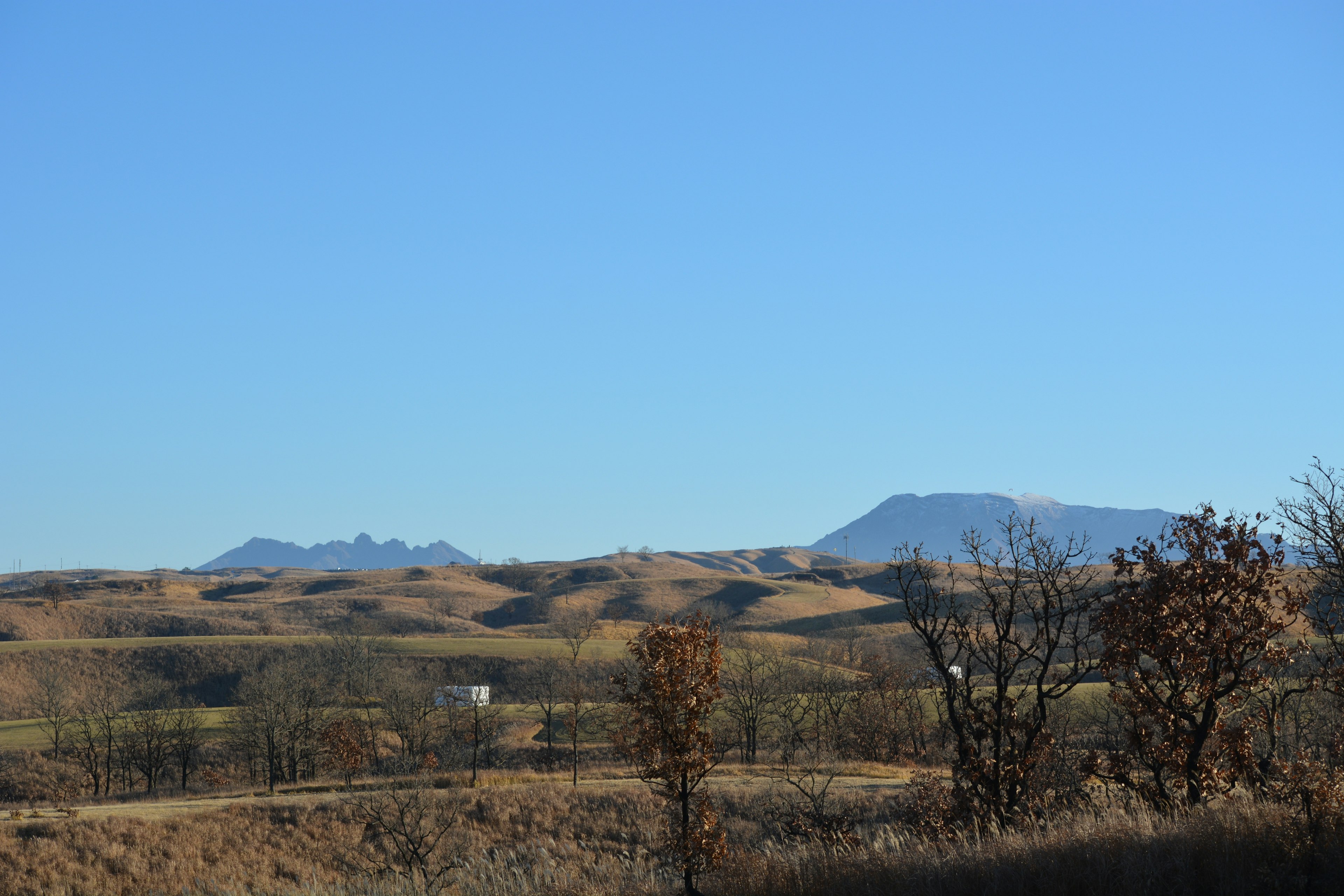 Paysage vallonné sous un ciel bleu avec des montagnes lointaines