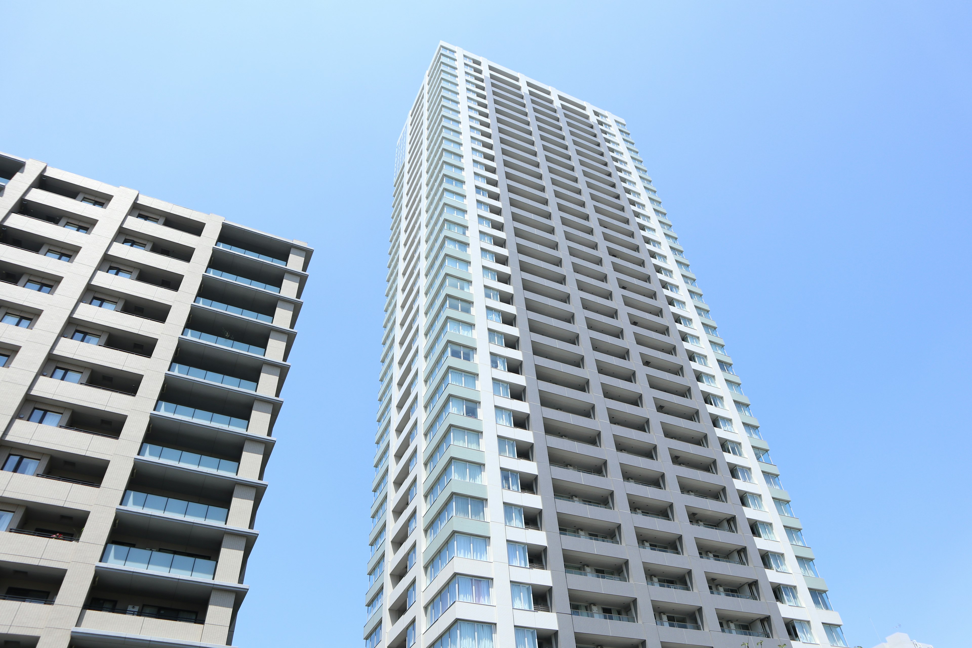 Modern skyscraper alongside a low-rise building under a clear blue sky