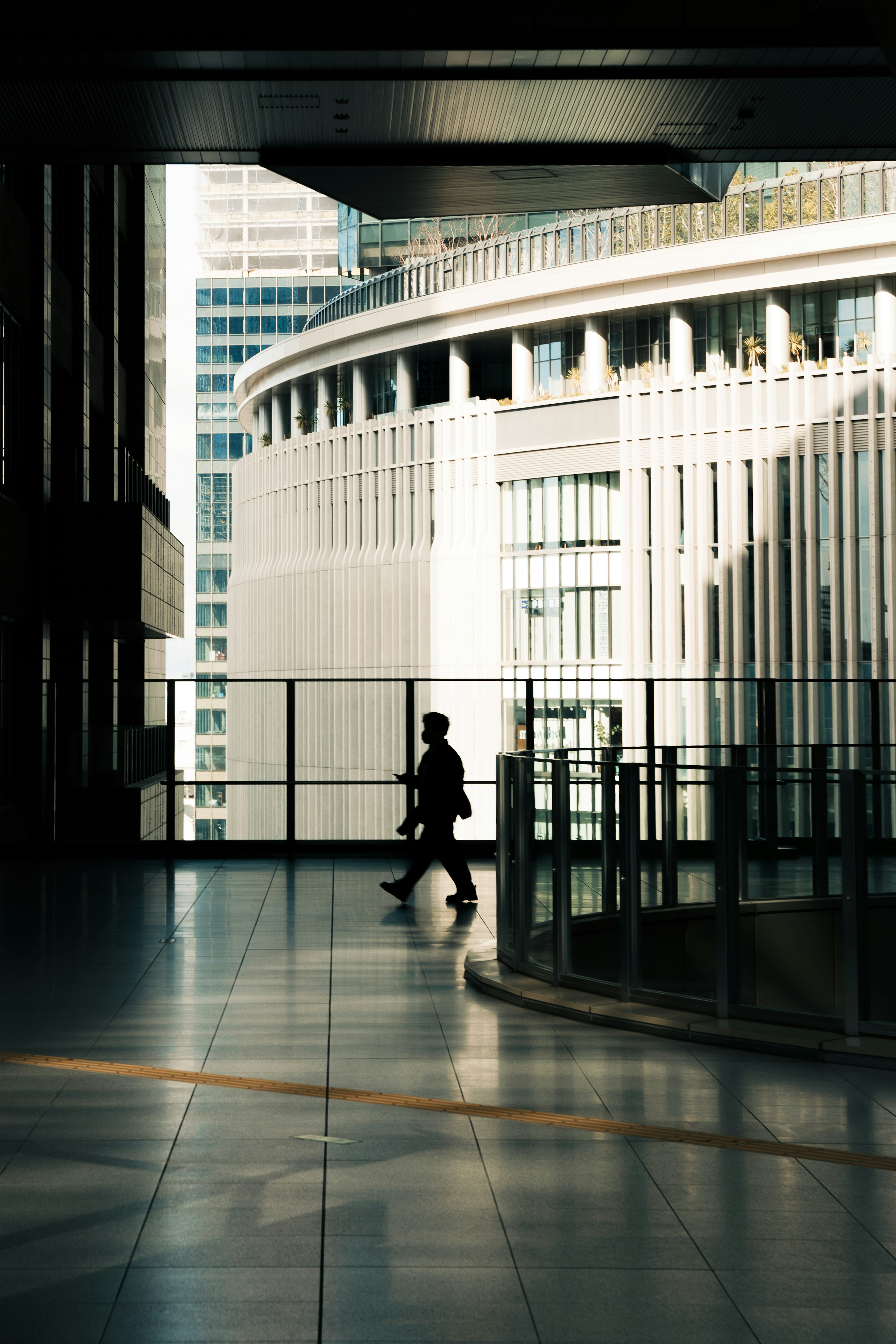 Silhouette d'une personne marchant entre des bâtiments avec une architecture moderne