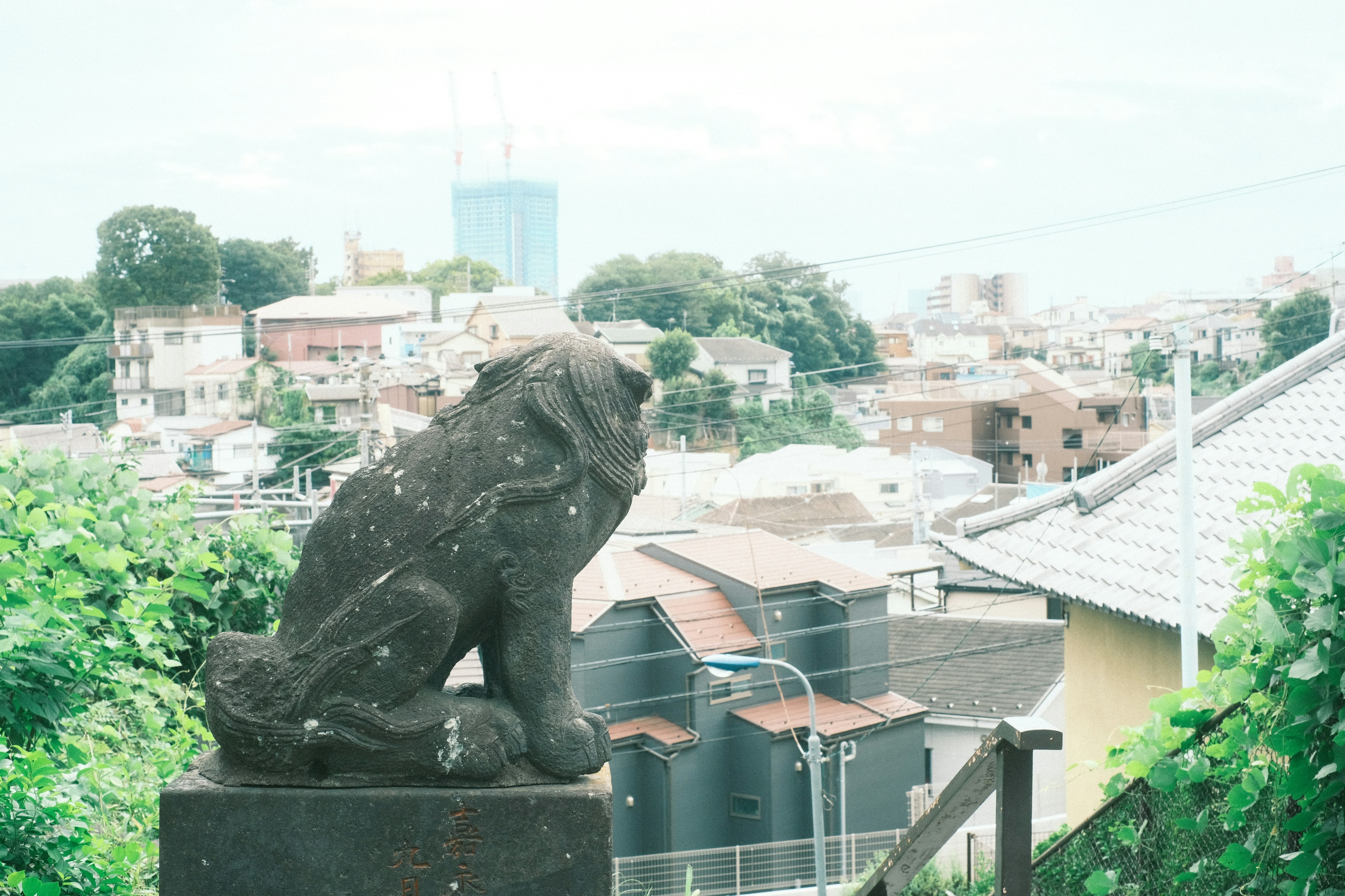 A stone lion statue sitting quietly with a cityscape in the background