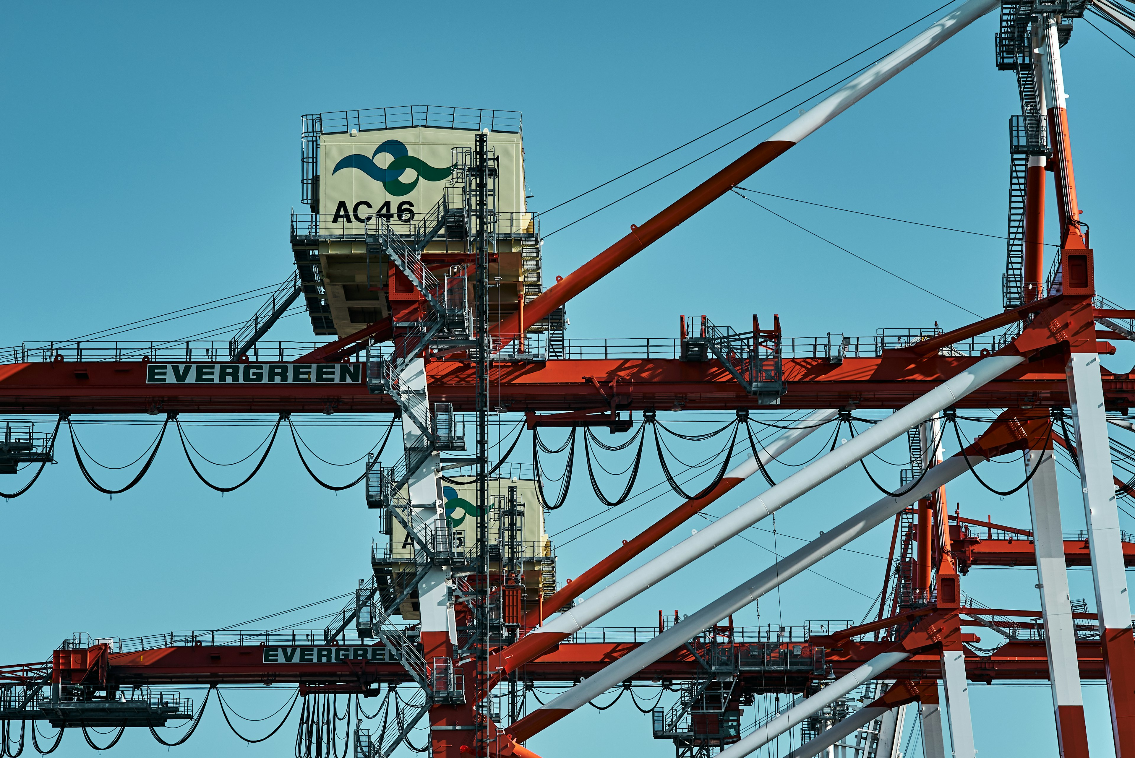 Port scene with red and white cranes and visible shipping containers