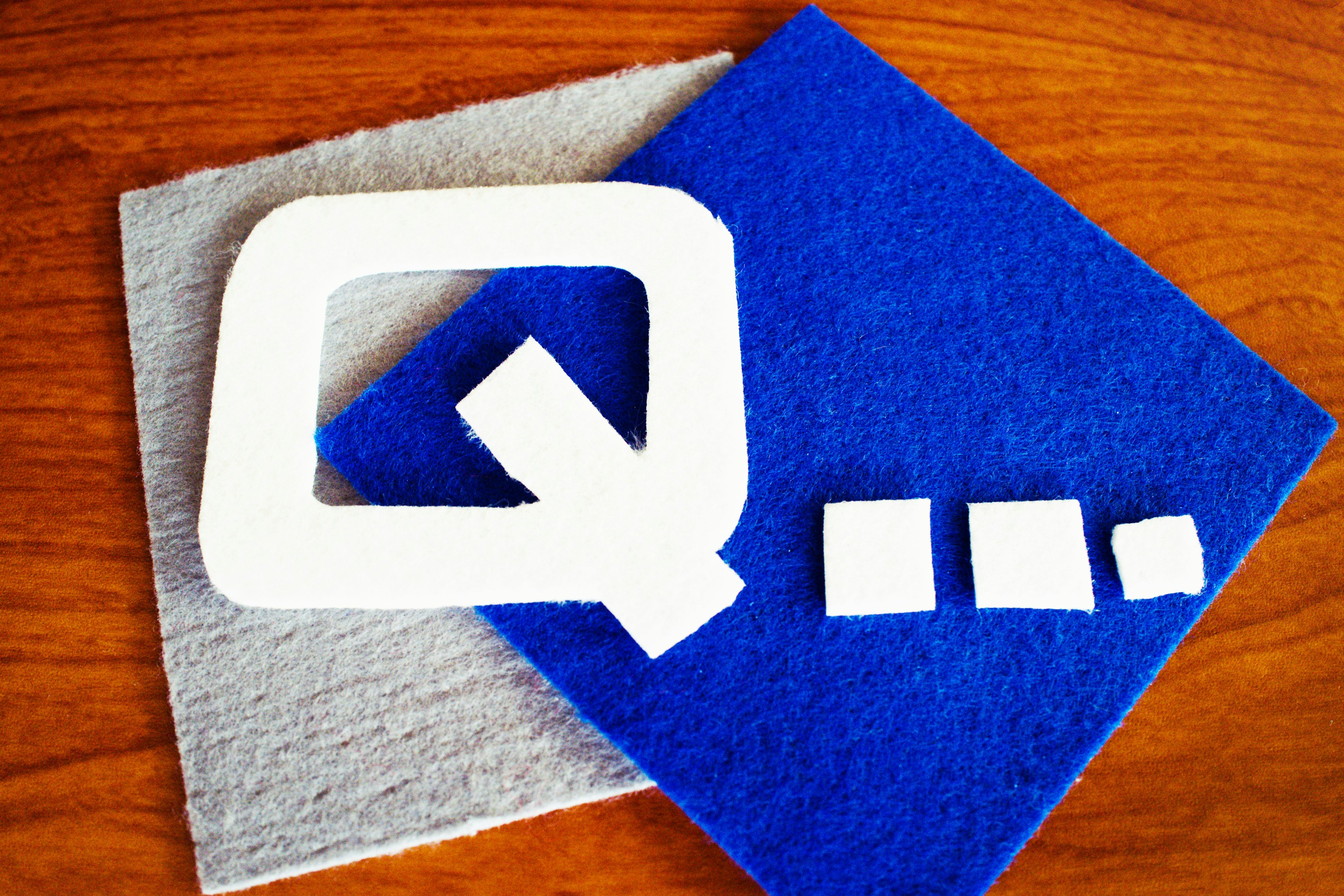 White letter Q on blue felt background with small white squares