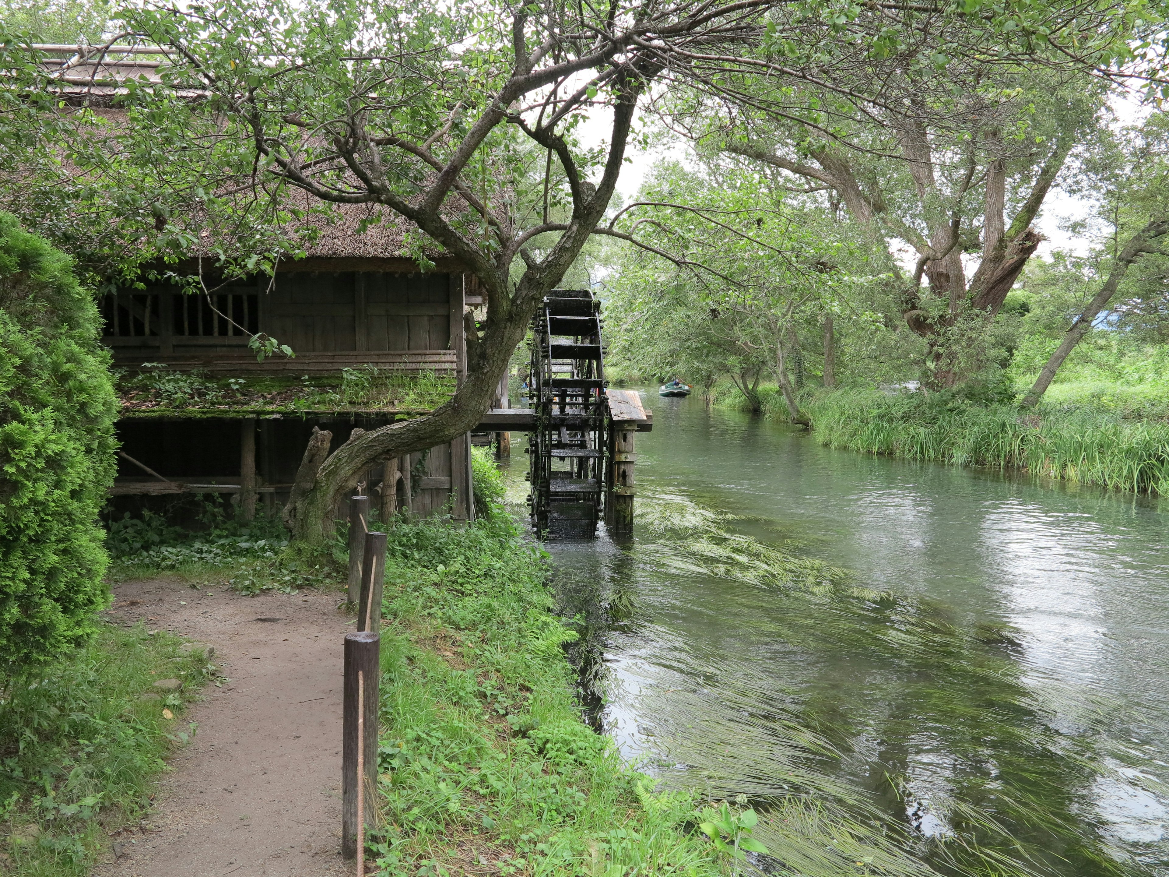 Una escena de río tranquila con un molino de agua y vegetación exuberante