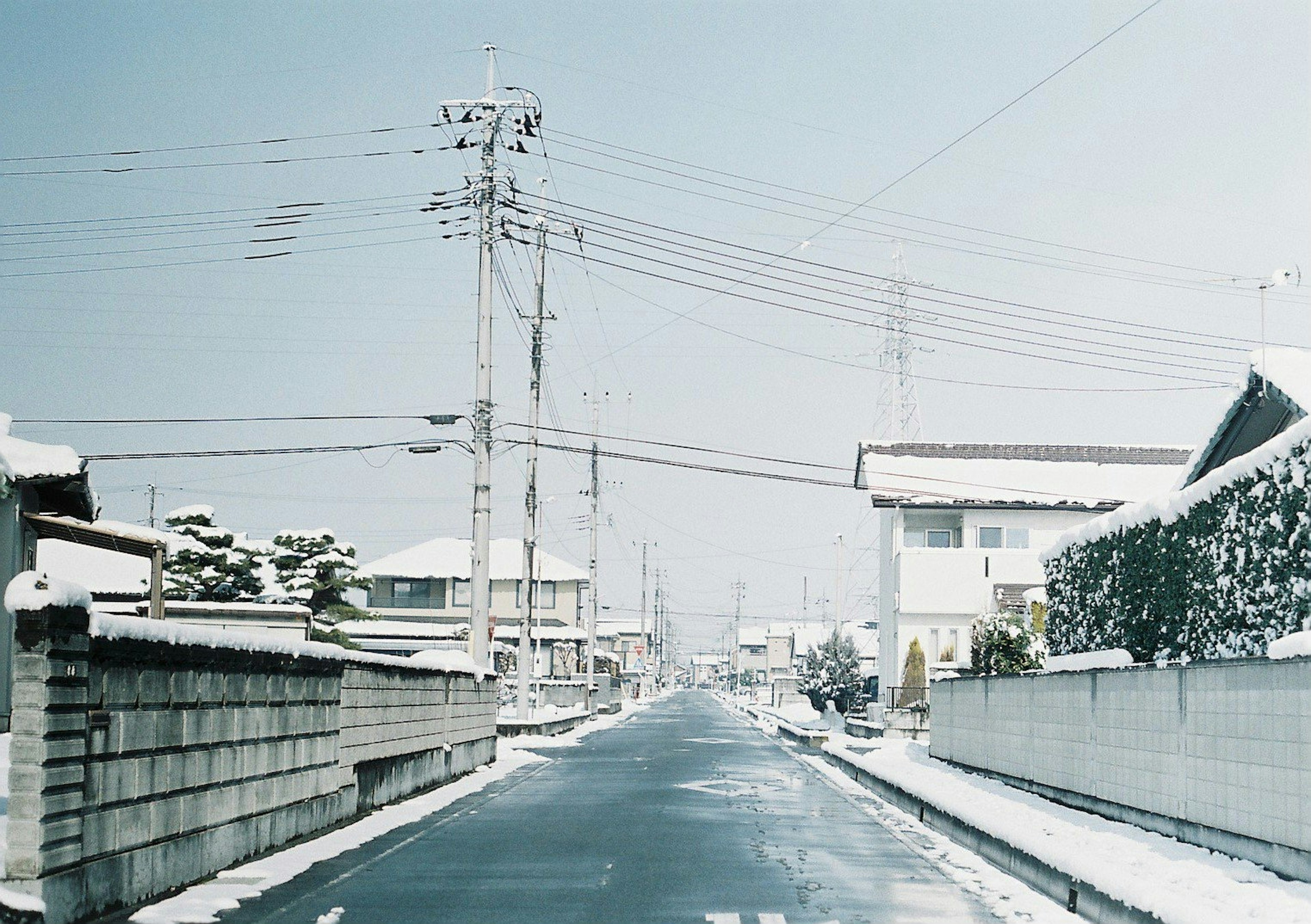 Escena de calle tranquila cubierta de nieve con postes eléctricos a lo largo de la carretera