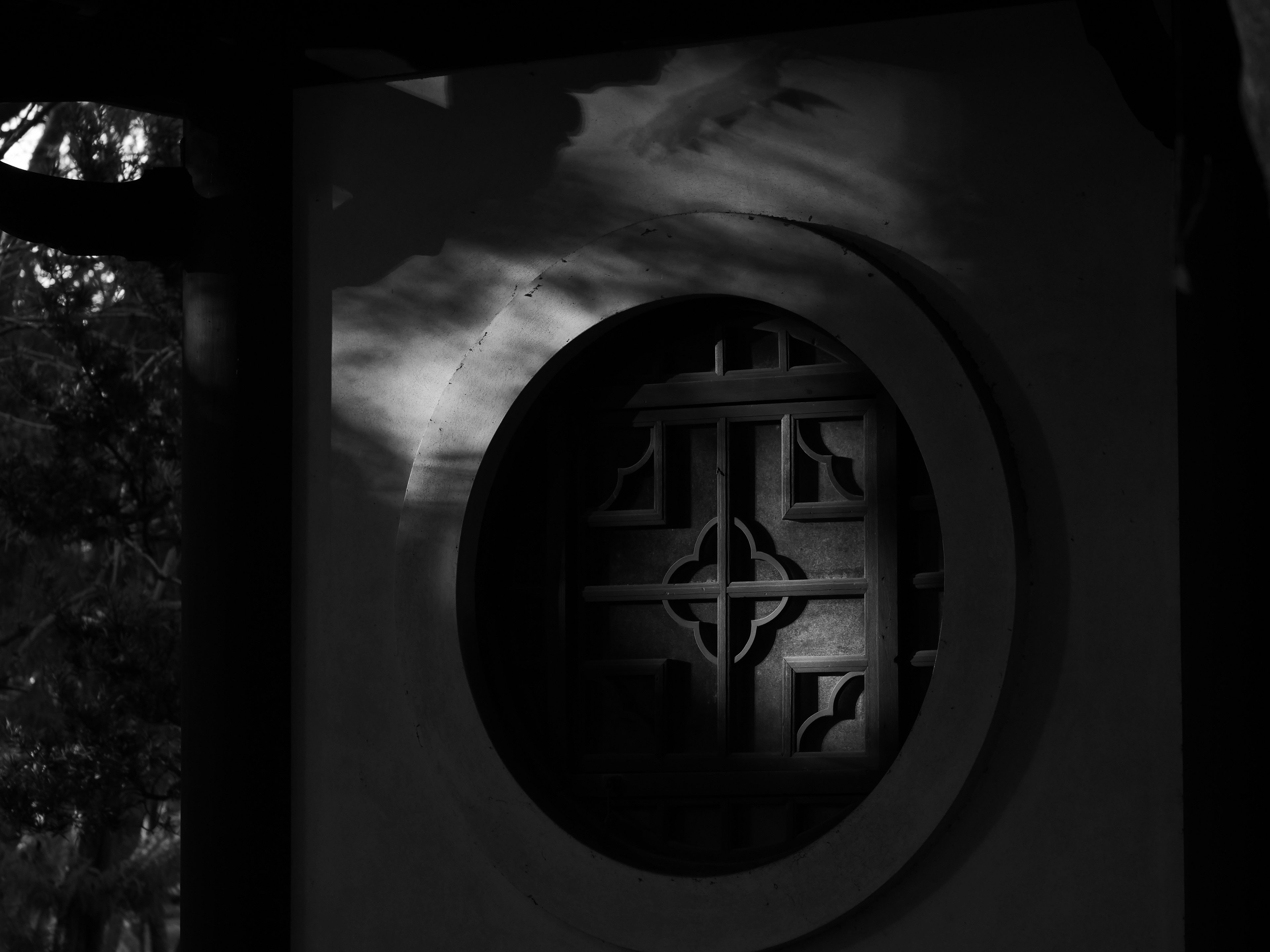 Circular window with intricate design and shadows in black and white