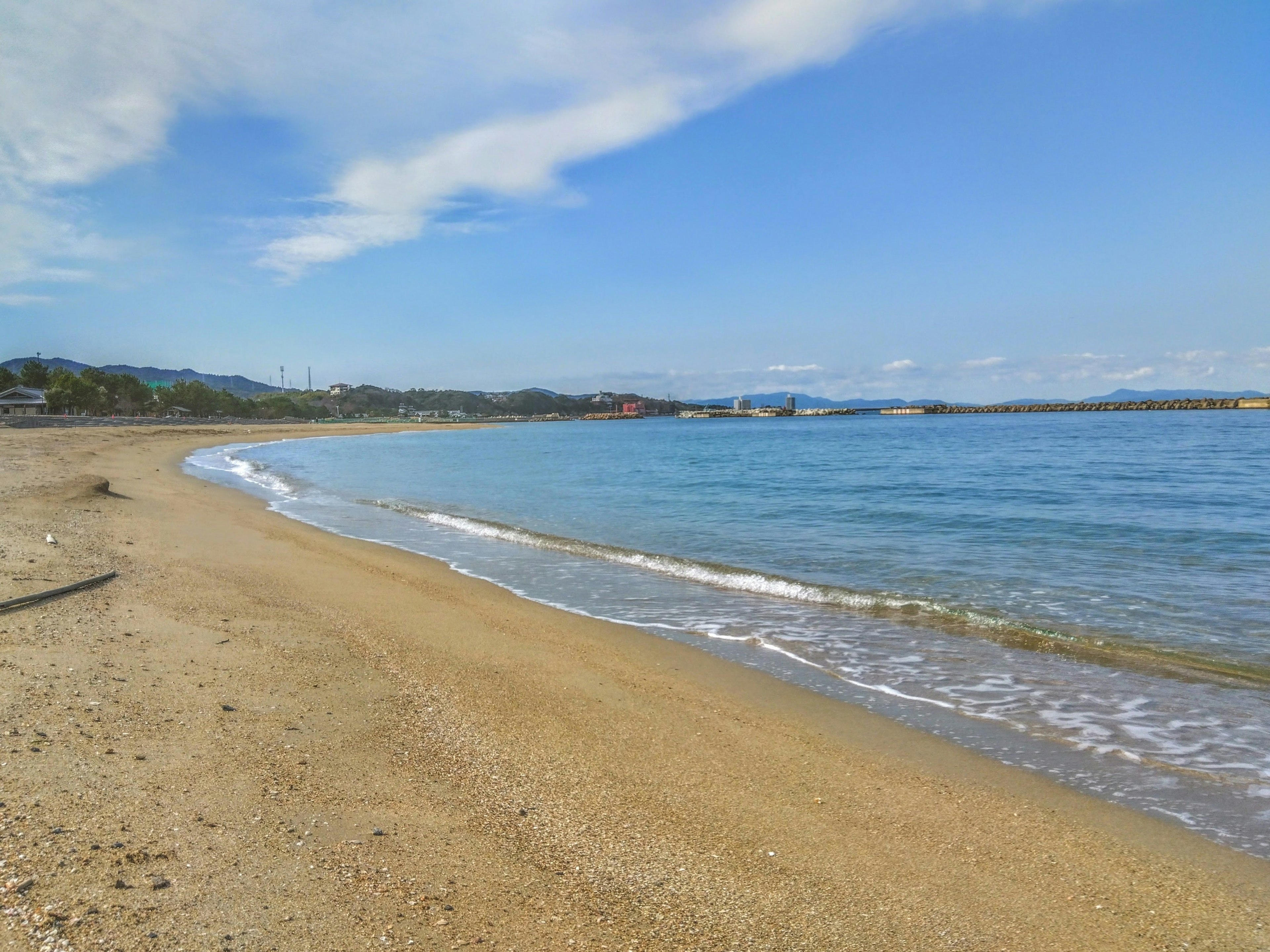 ทิวทัศน์ชายหาดที่สวยงามพร้อมคลื่นนุ่มนวลและท้องฟ้าสีฟ้า