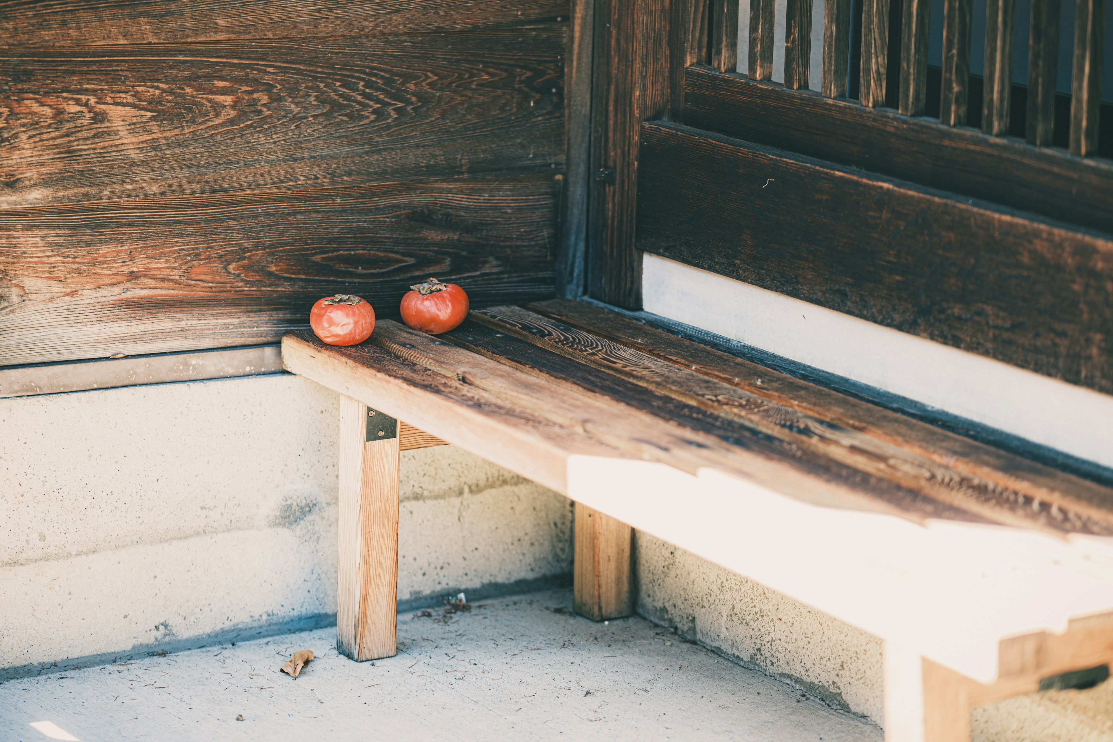 Foto di due mele rosse appoggiate su una panchina di legno