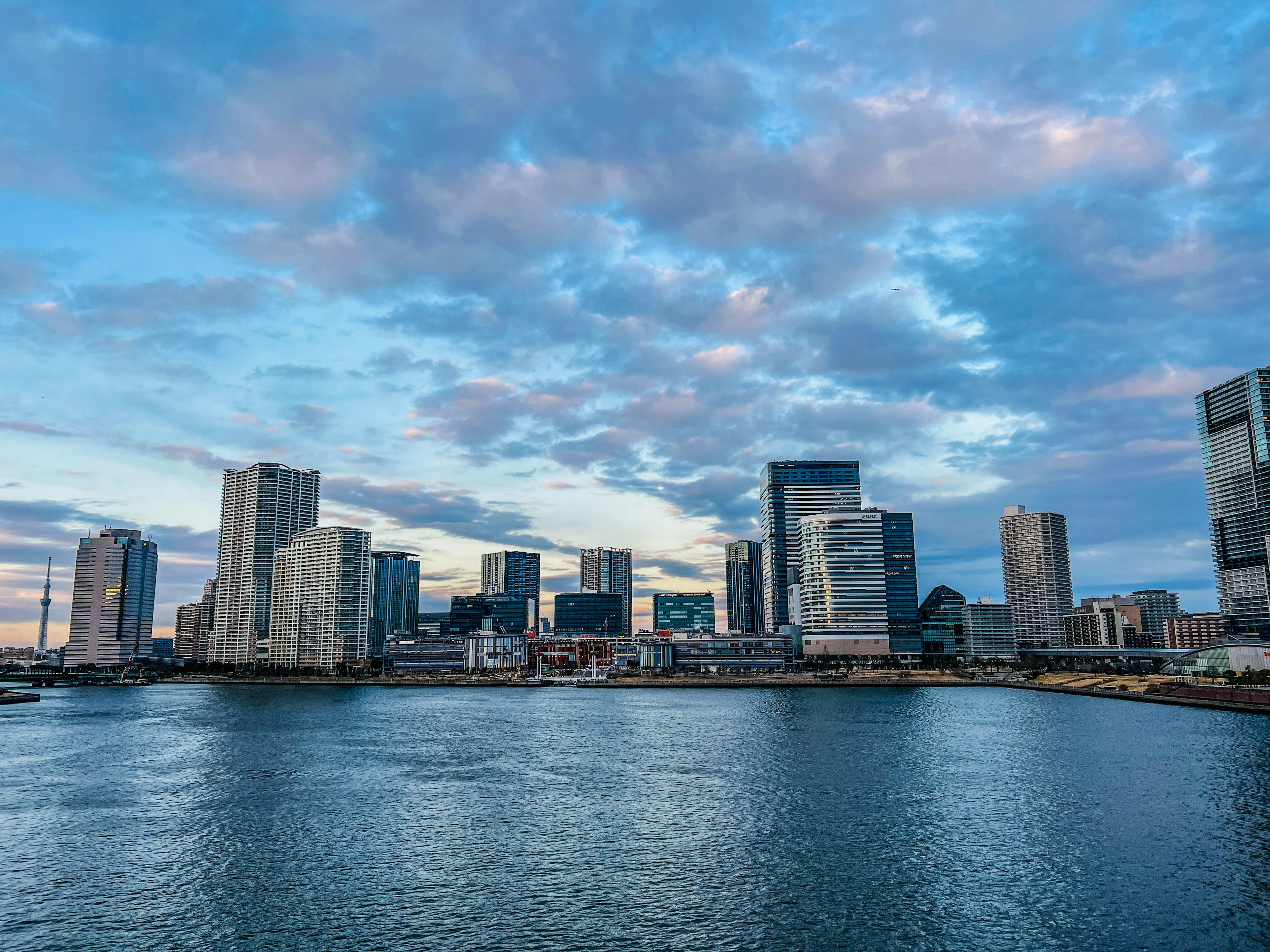 Moderne Skyline spiegelt sich im blauen Wasser mit Wolken