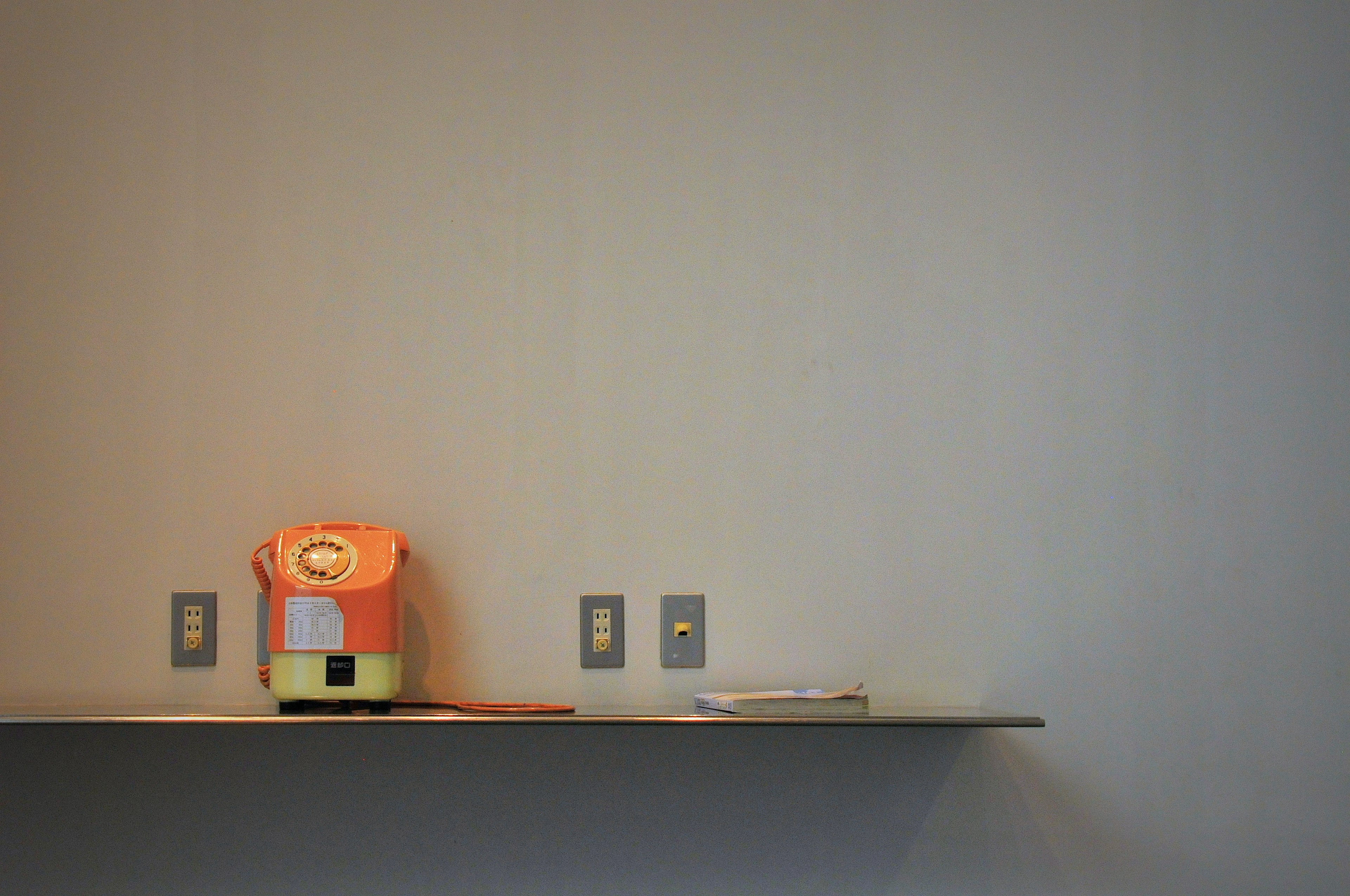 Image of a simple wall shelf with an orange device and a book