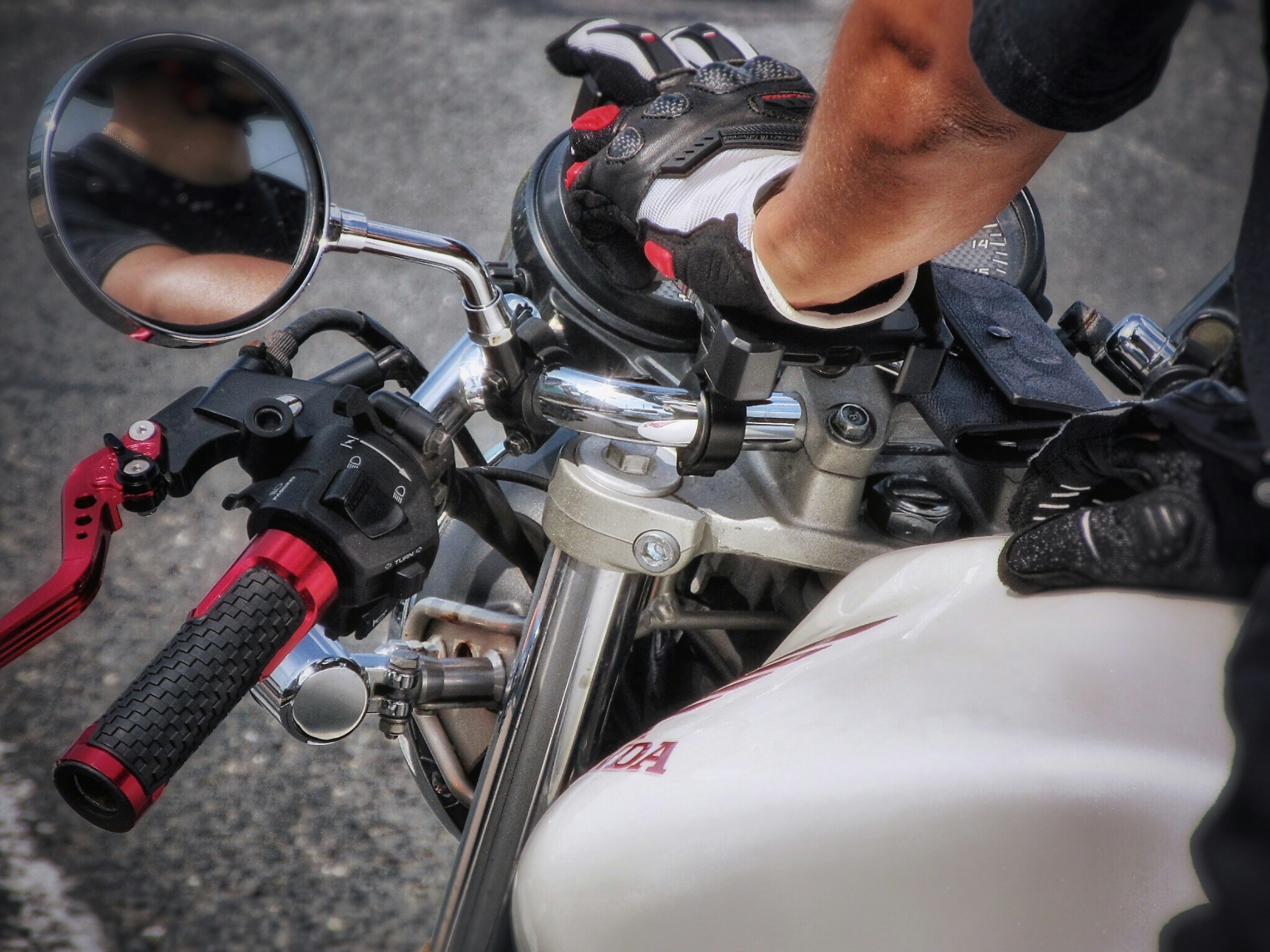 Close-up of a hand adjusting the throttle on a motorcycle with gloves