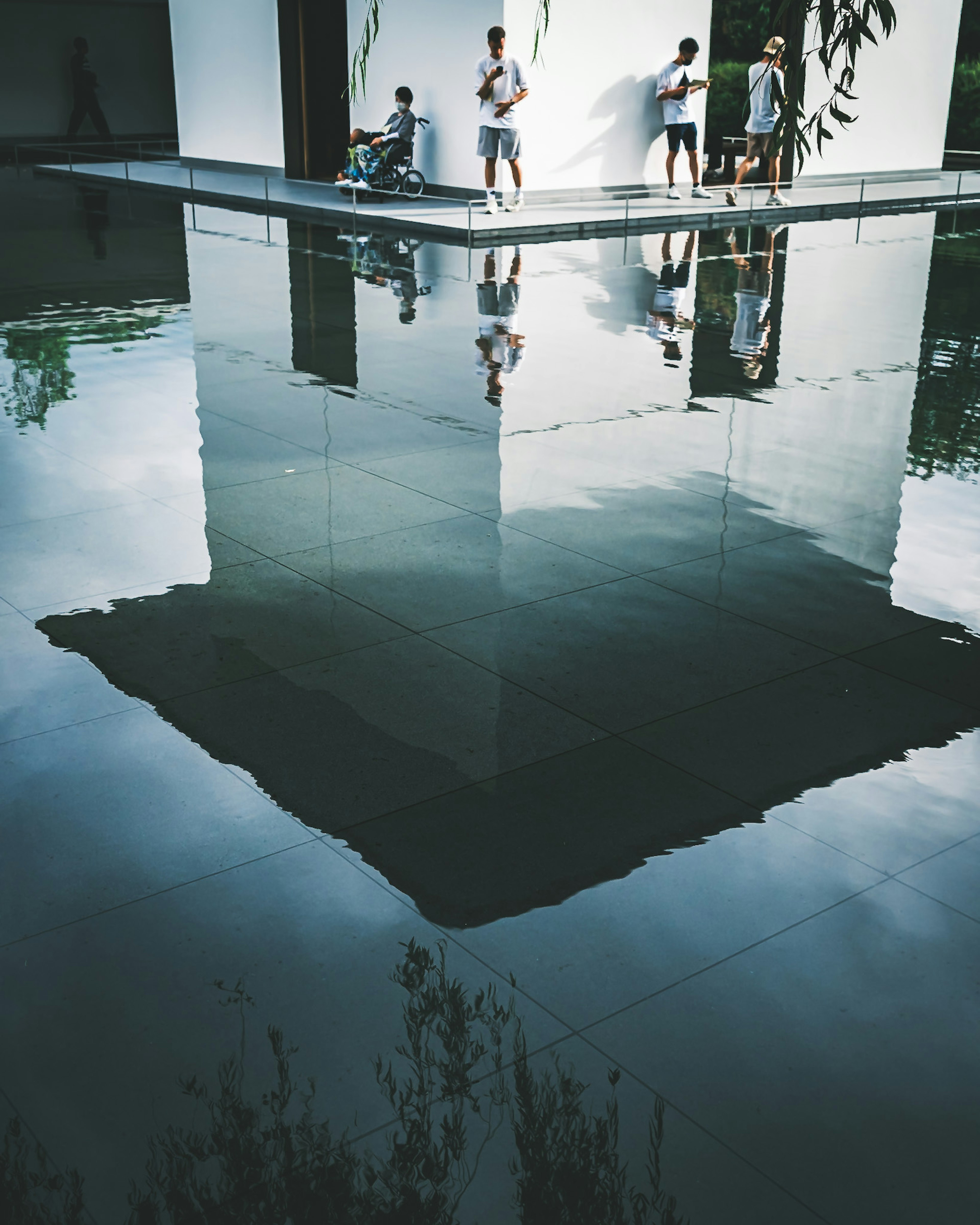 Modern building reflected in water with people