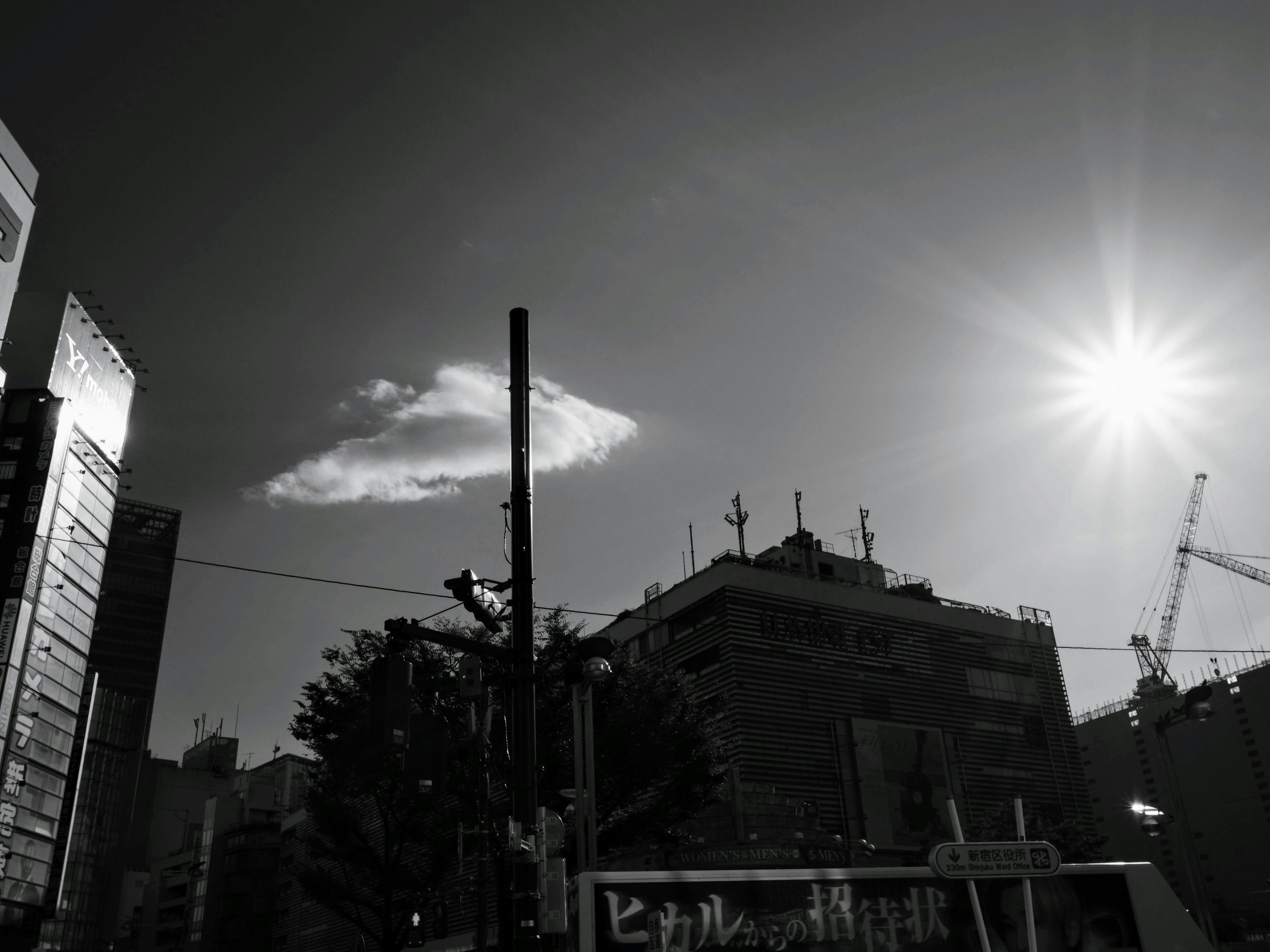 モノクロの都市景観に浮かぶ雲と太陽の光