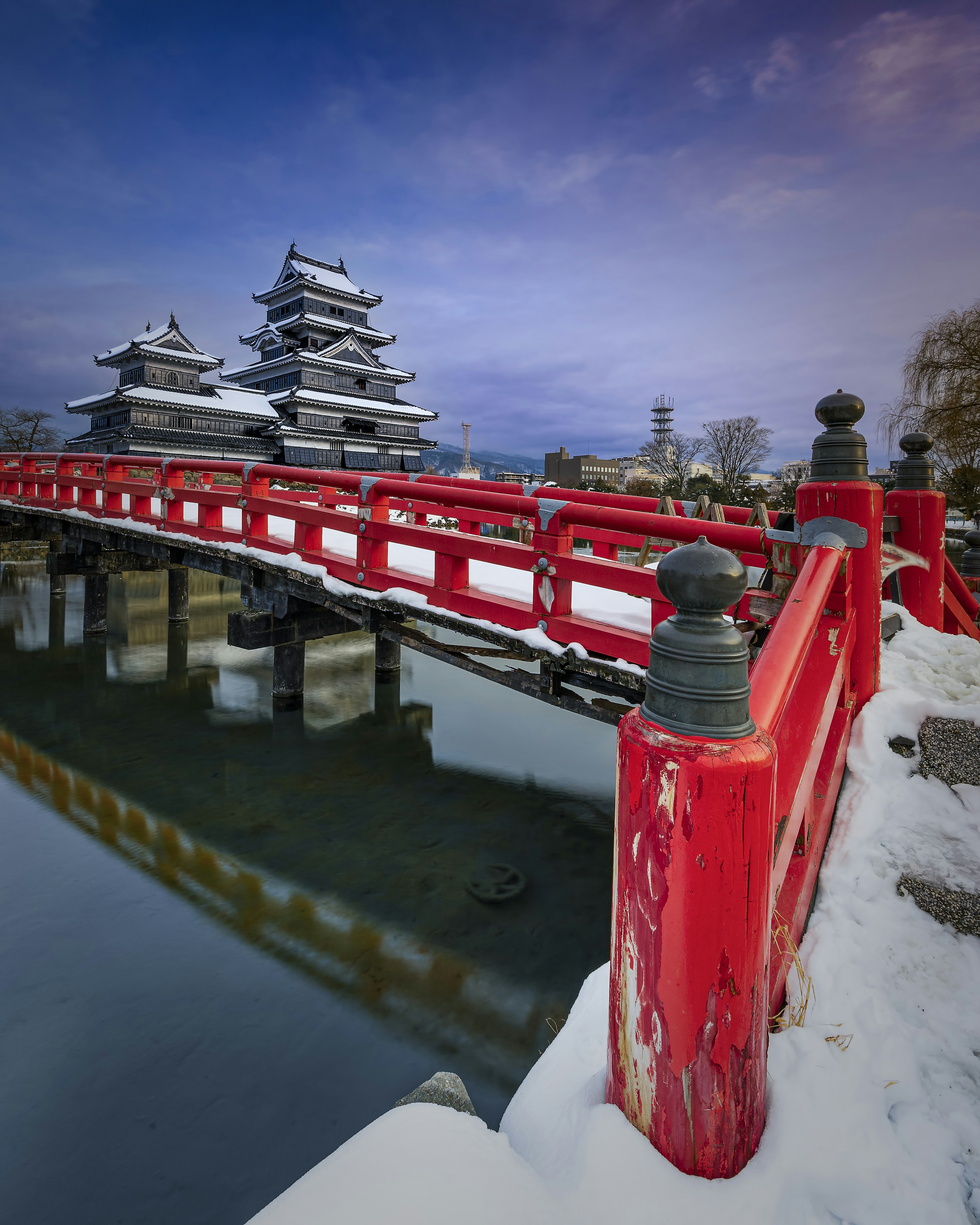 赤い橋と雪に覆われた松本城の風景