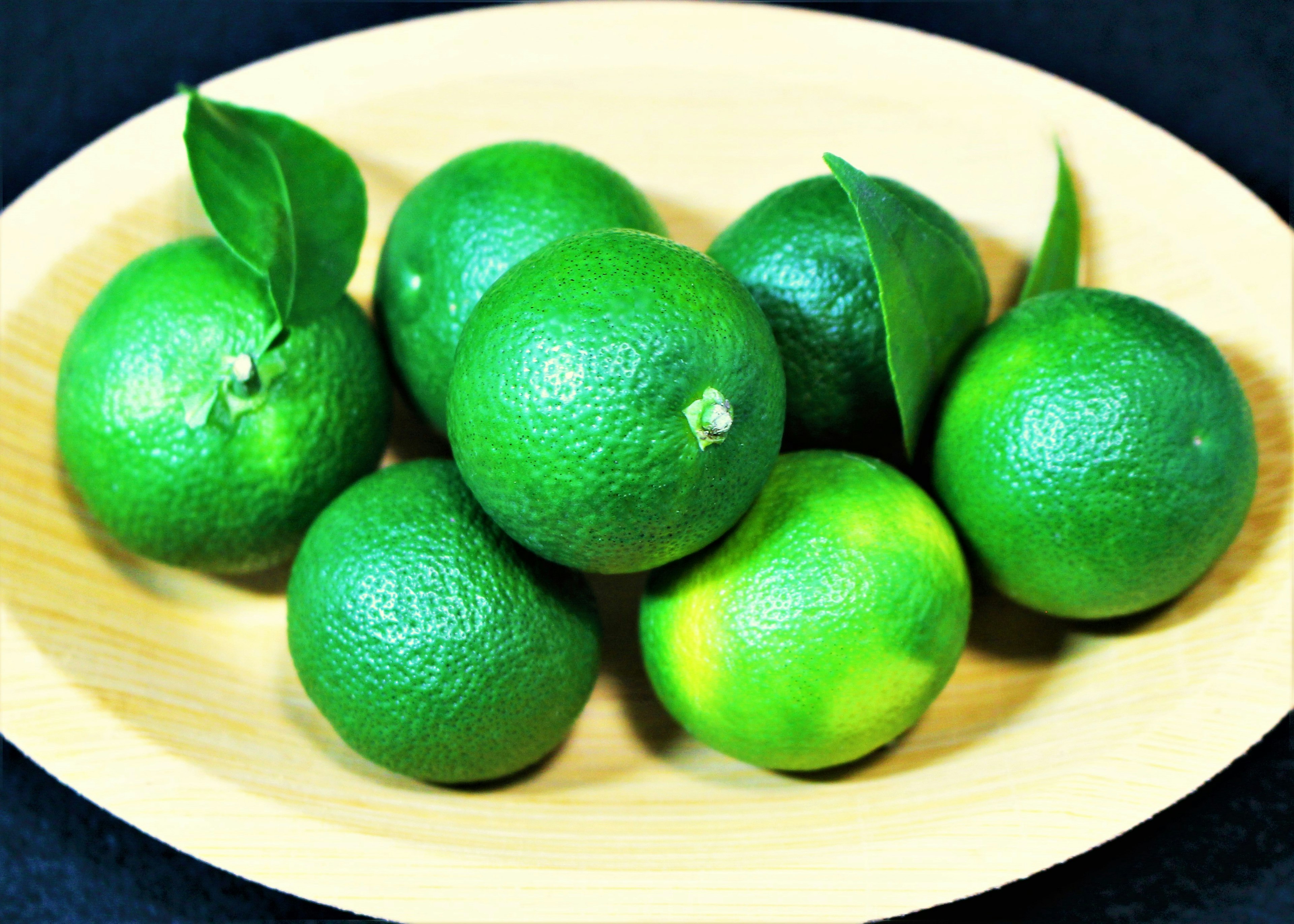 Une assiette en bois remplie de fruits citrus verts