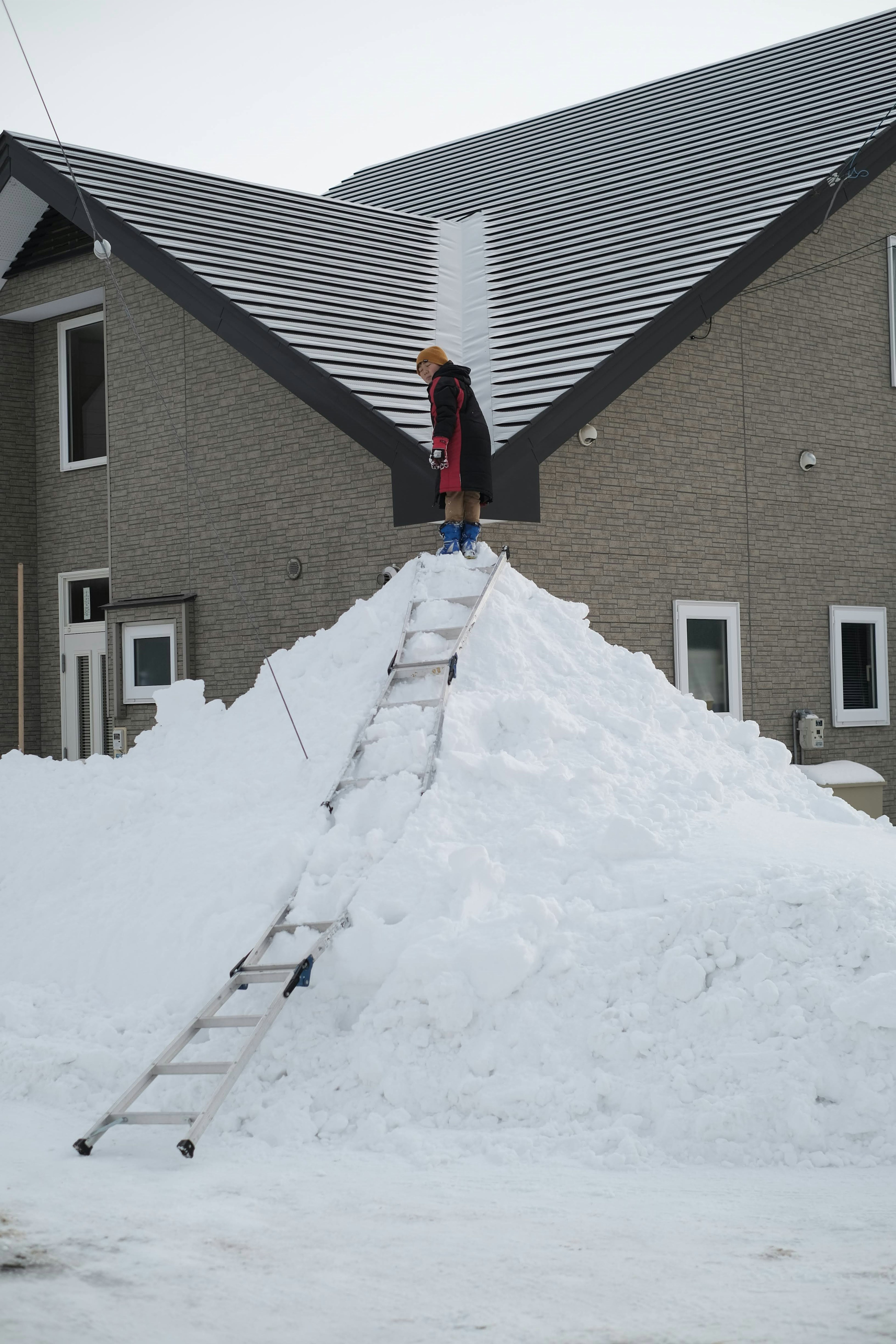 站在雪堆上的人和梯子