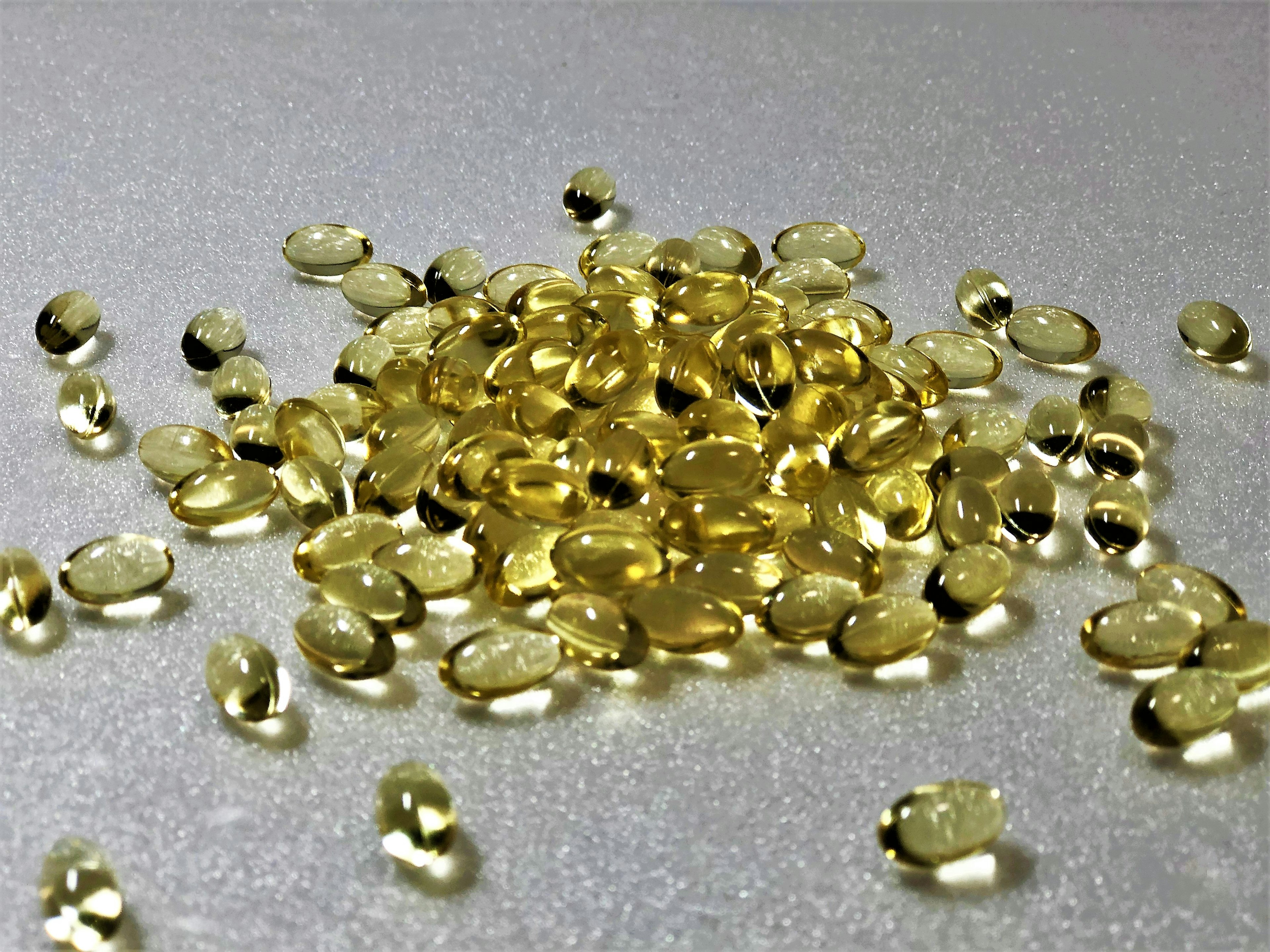 A pile of yellow capsules scattered on a silver surface