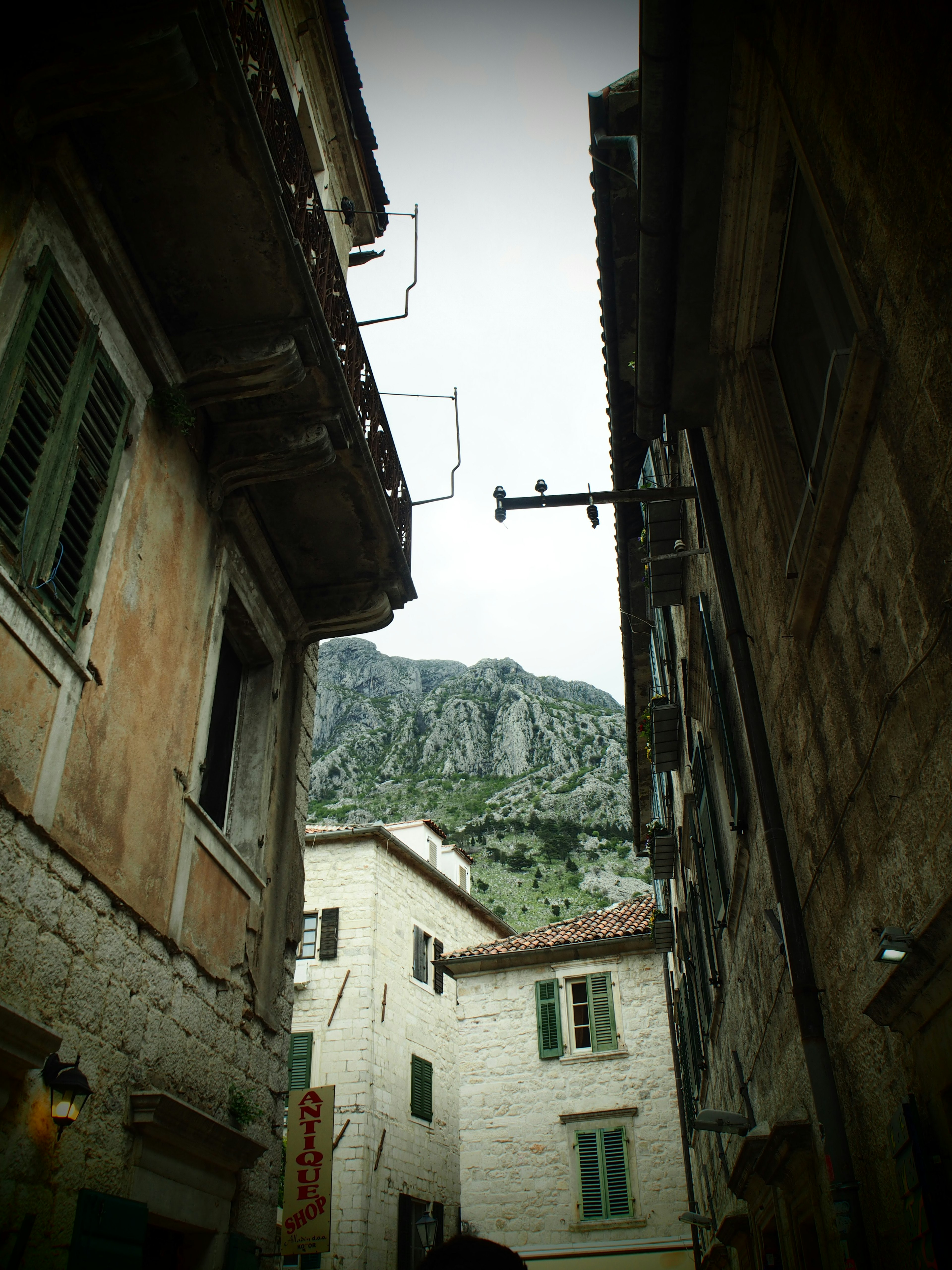 Strada stretta in pietra con edifici antichi e montagne sullo sfondo