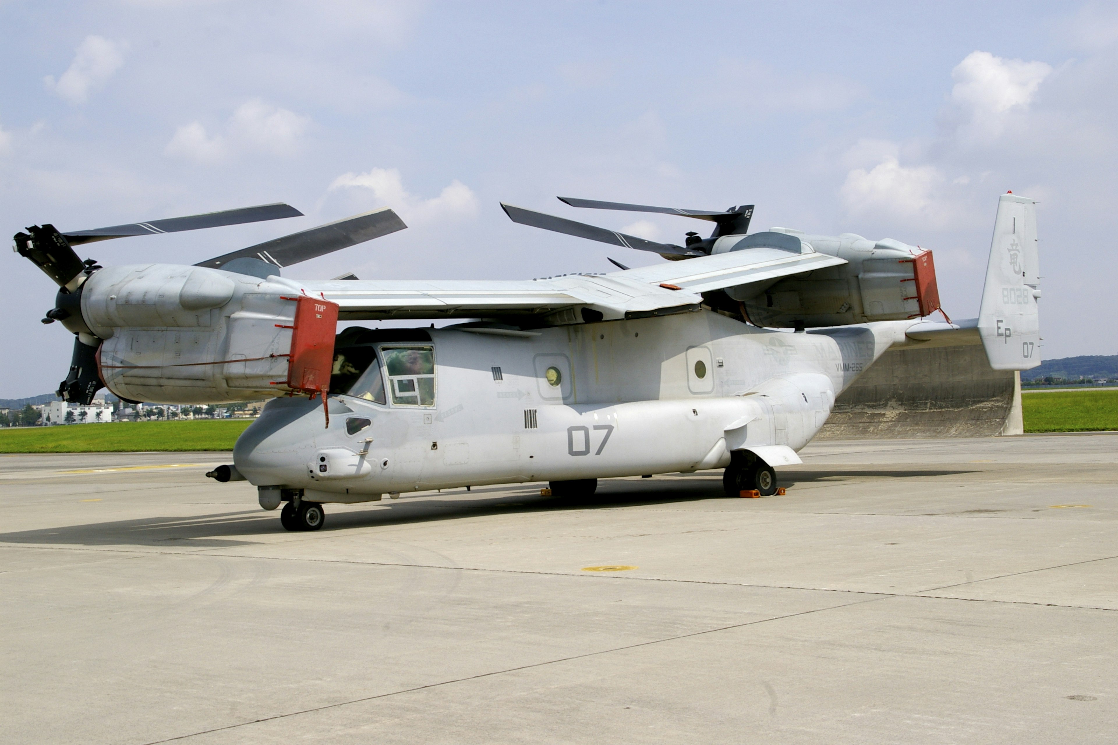 MV-22 Osprey aircraft parked on the tarmac under a bright sky