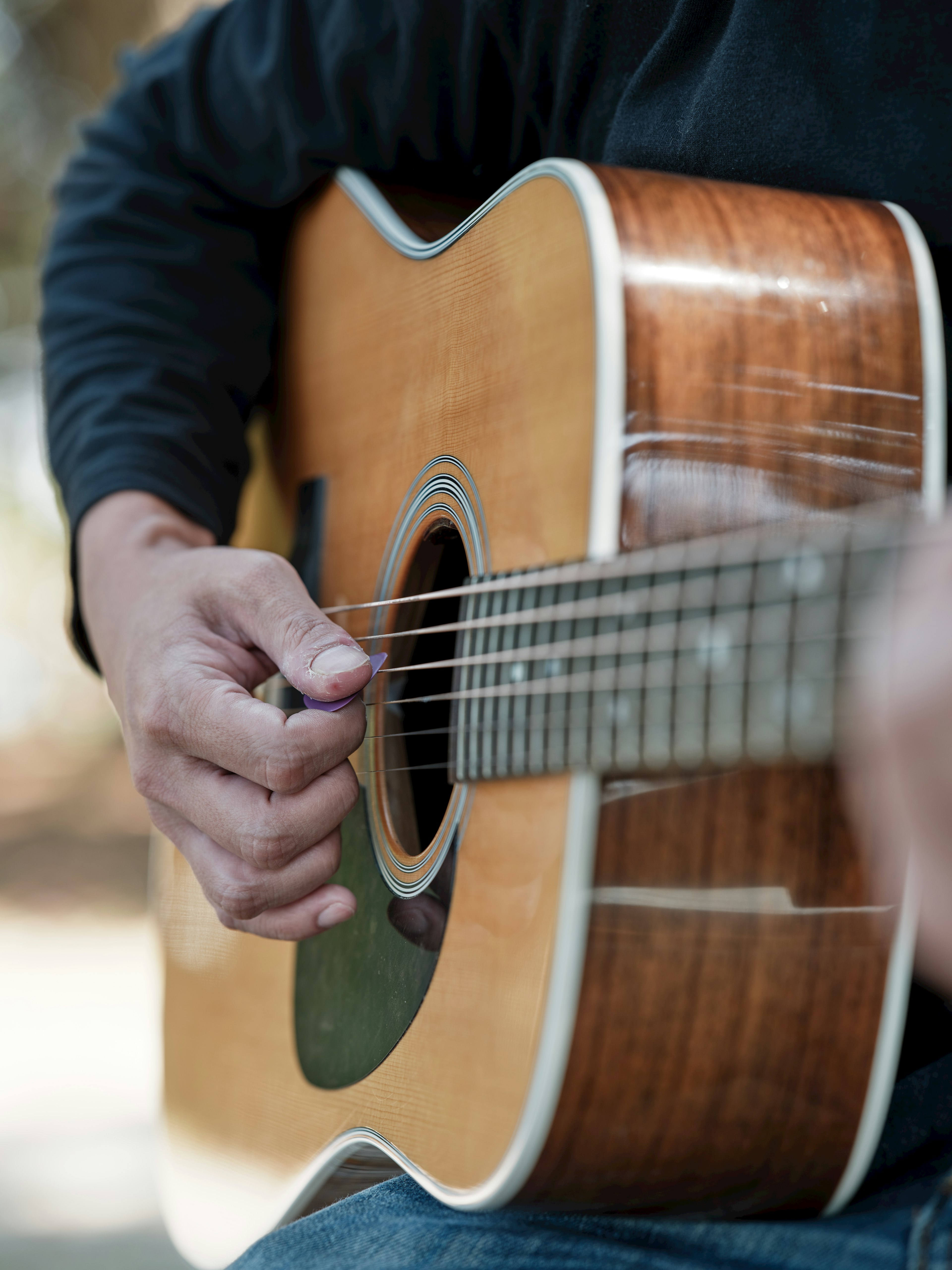 Close-up tangan yang memainkan gitar akustik