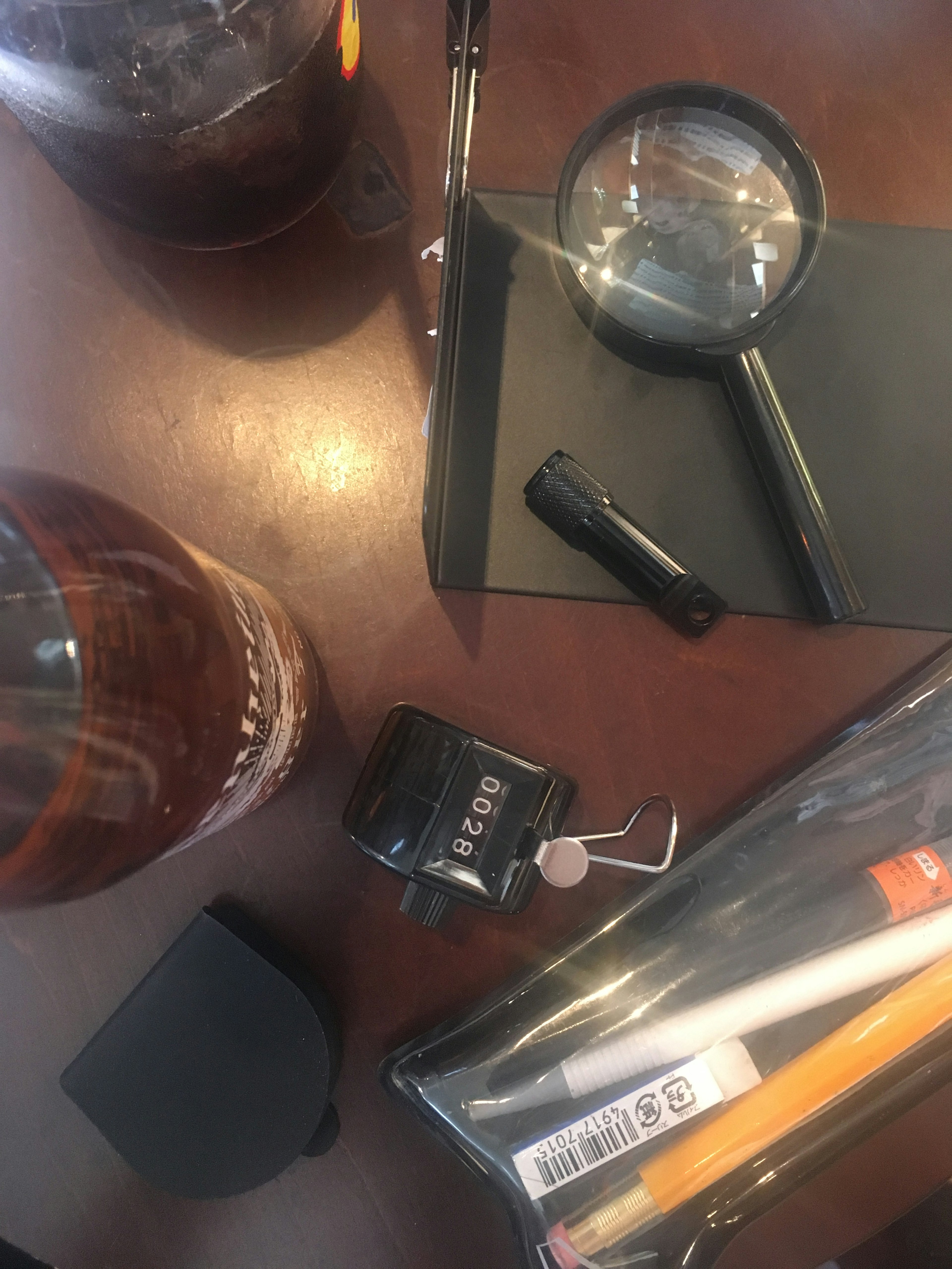 Une collection de fournitures de bureau et de boissons sur une table comprenant une loupe, un stylo noir, un carnet et une tasse