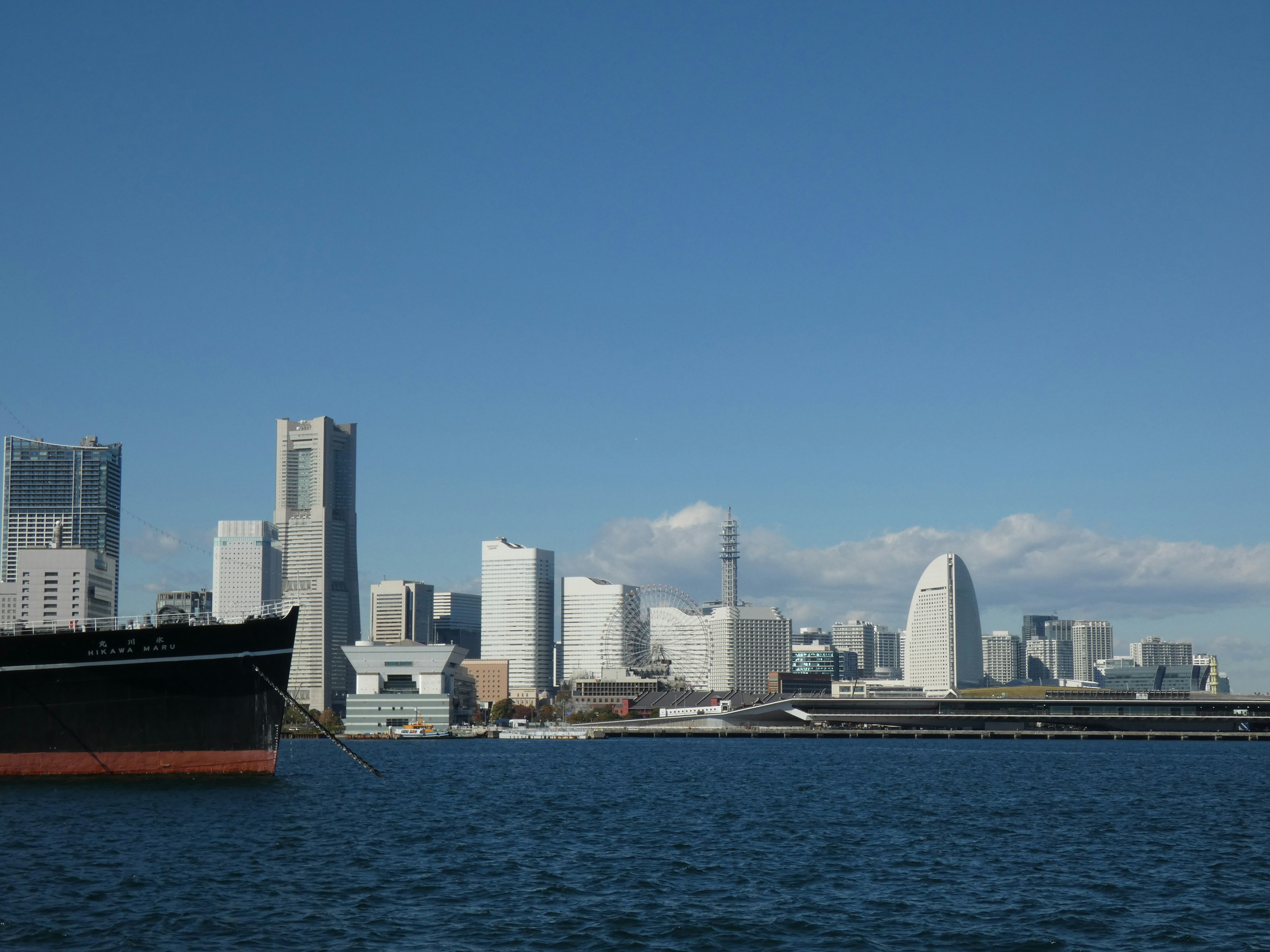 Blick auf die Skyline von Yokohama mit einem Schiff im Vordergrund und klarem blauen Himmel