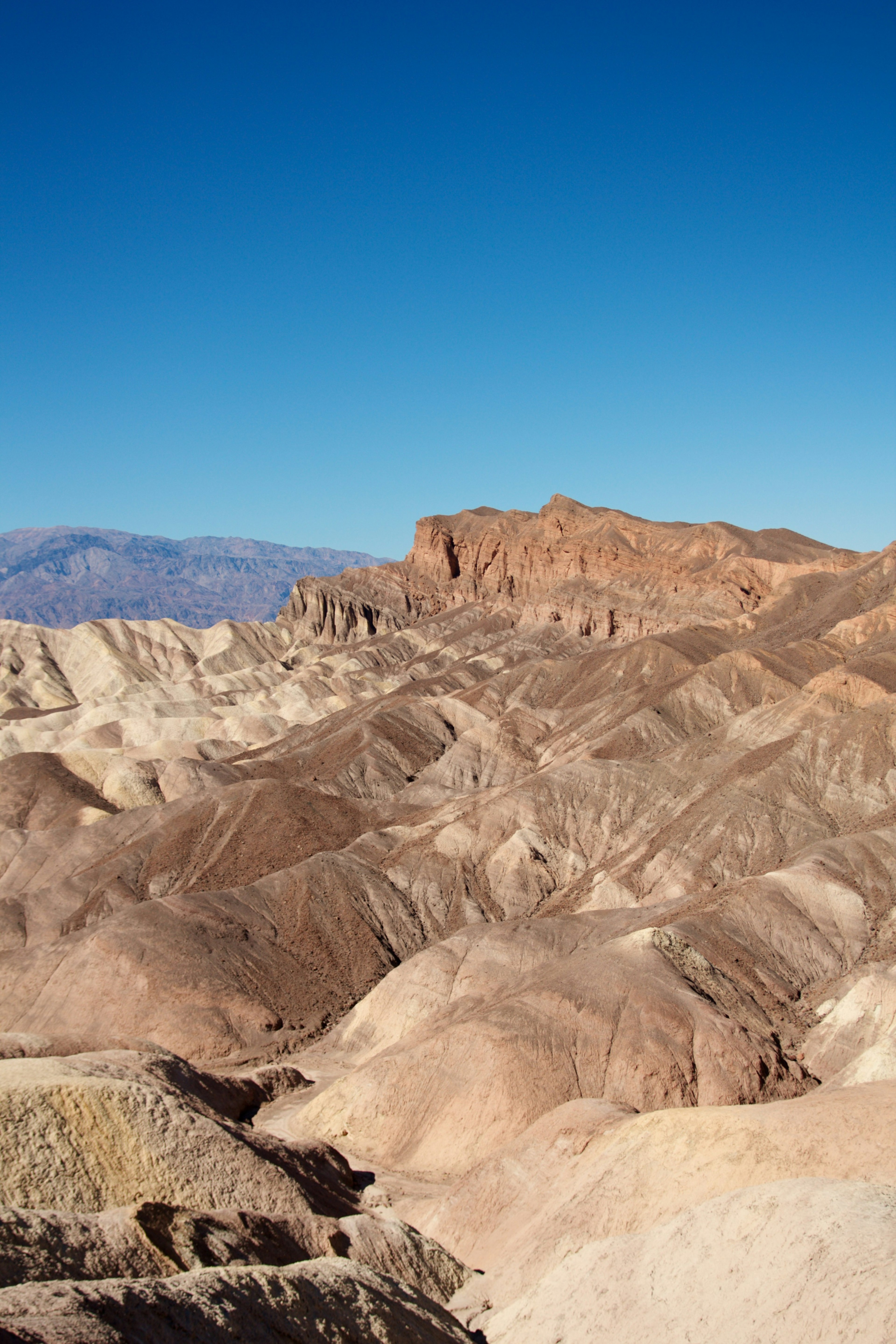 A rugged landscape with layered brown hills under a clear blue sky