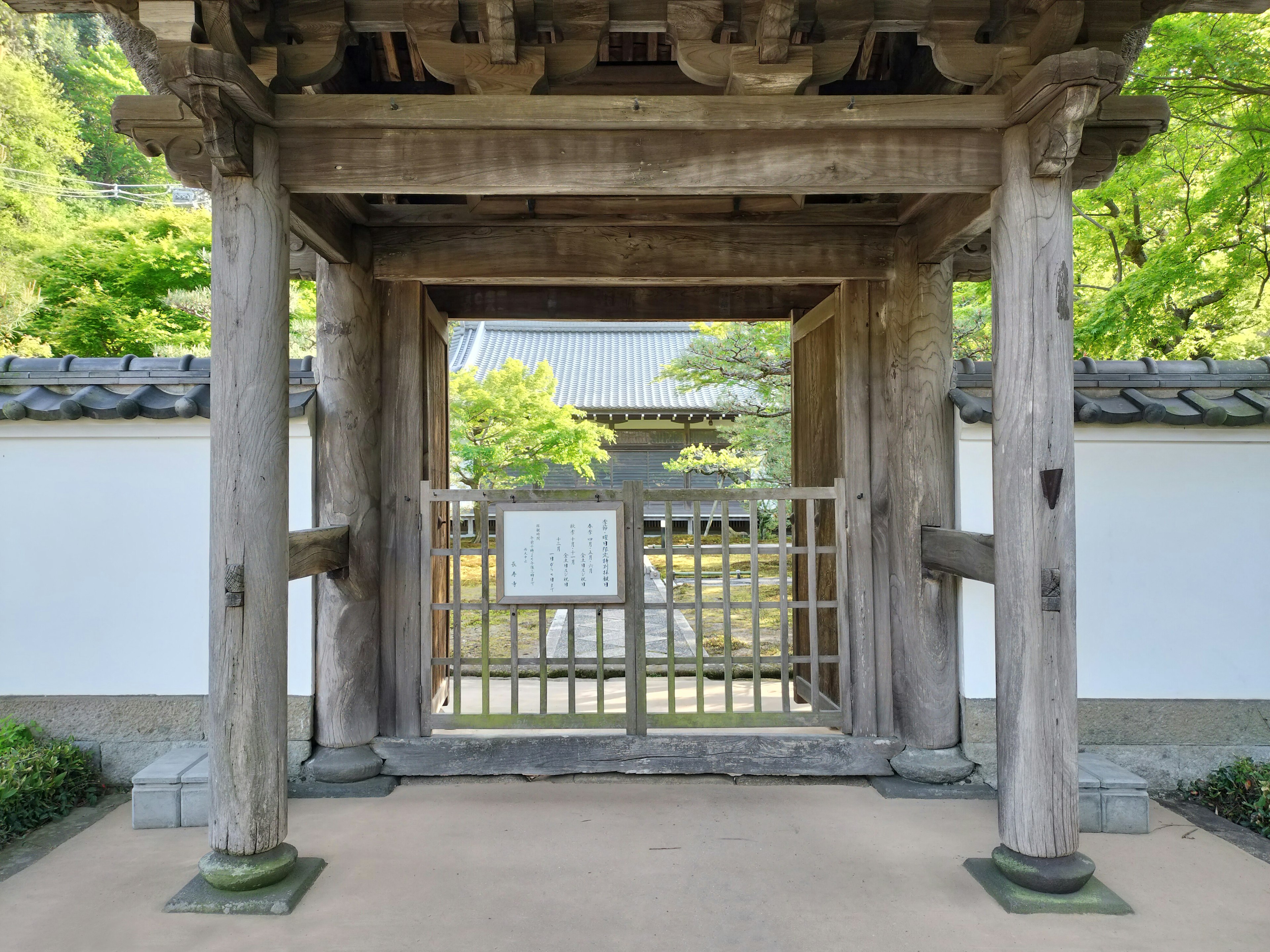 Pintu kayu dengan dinding putih di pintu masuk taman Jepang