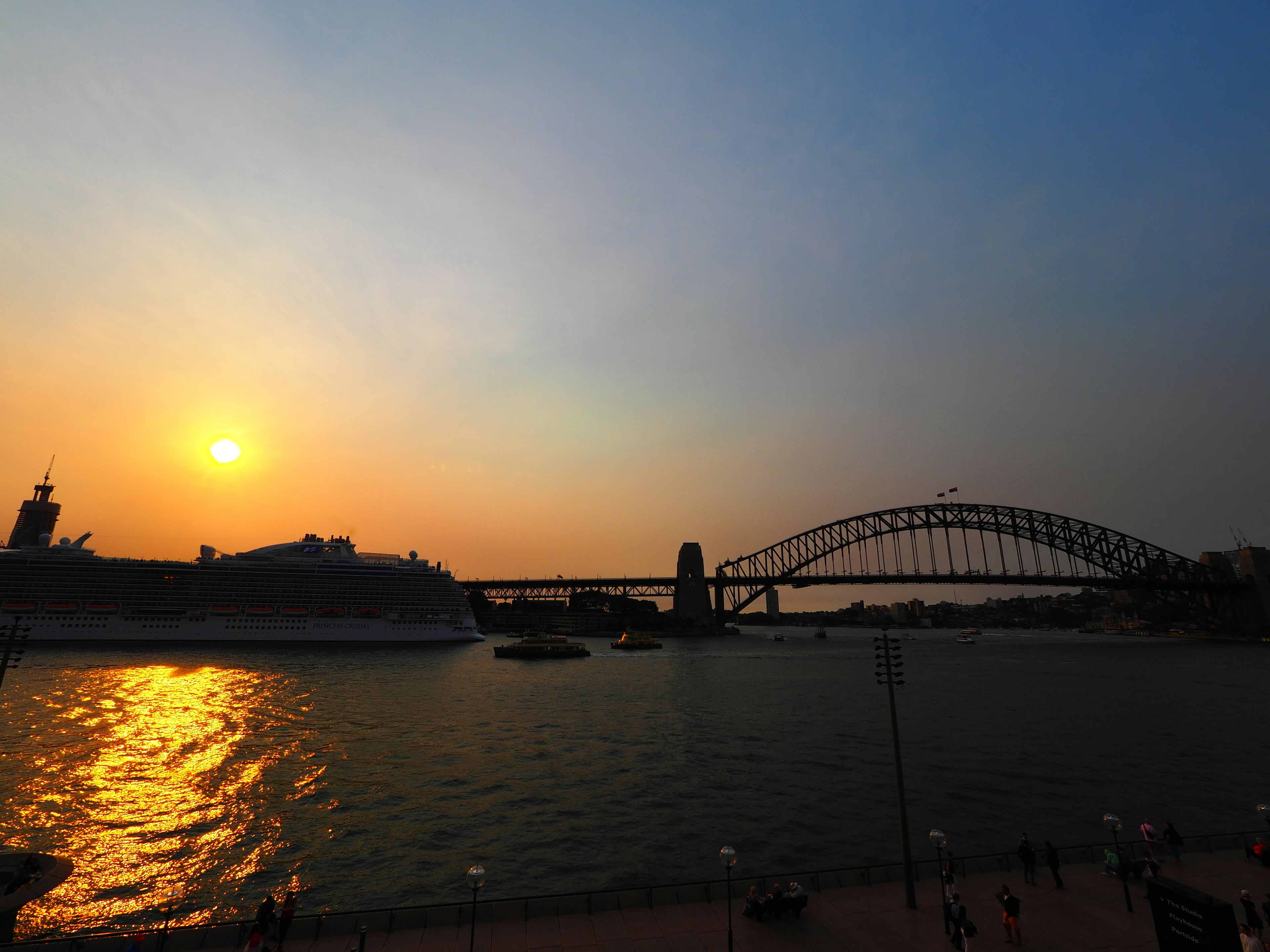 シドニーのハーバーブリッジと夕日が映る水面の風景