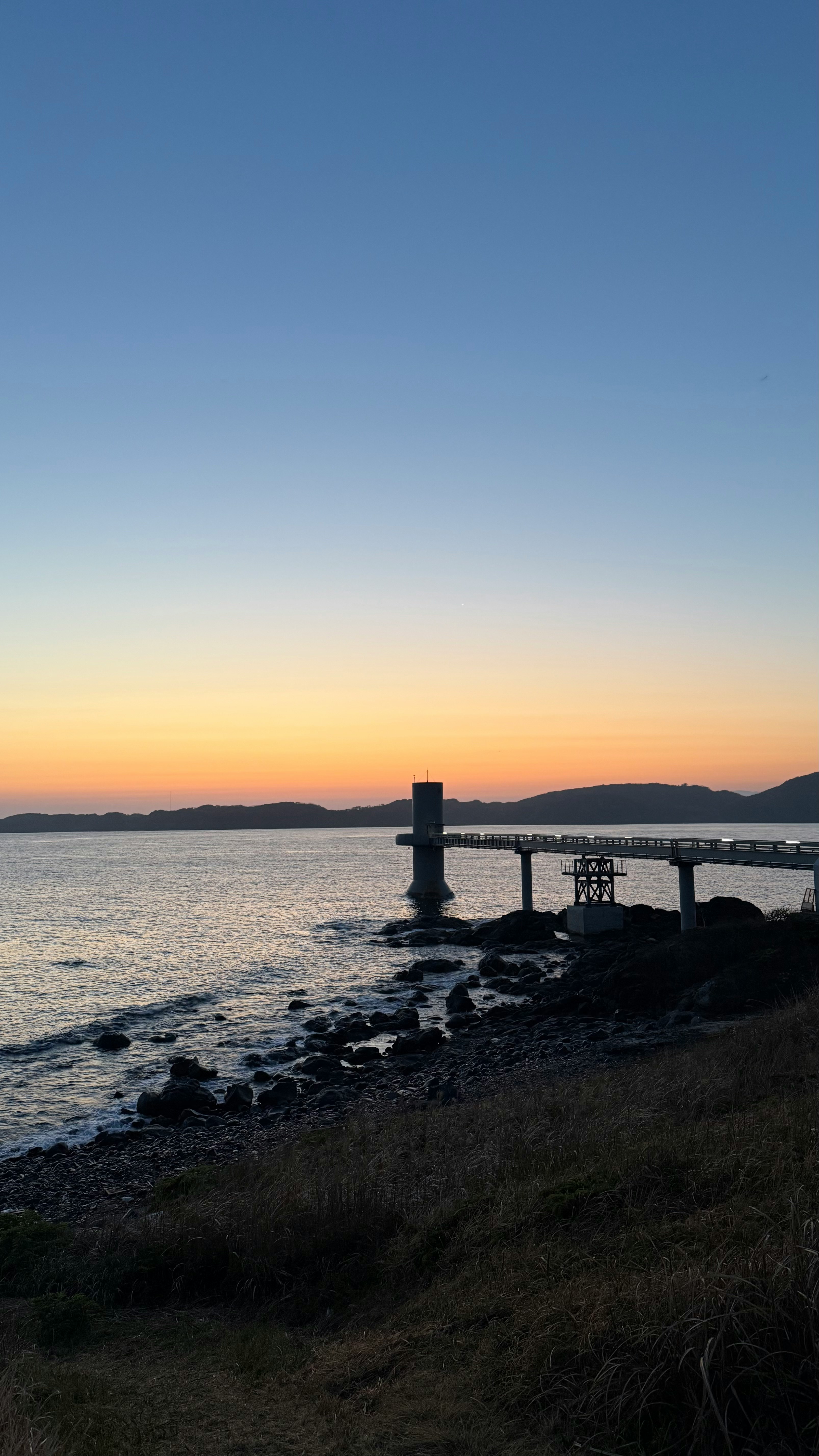 海岸の夕暮れに立つ桟橋と波