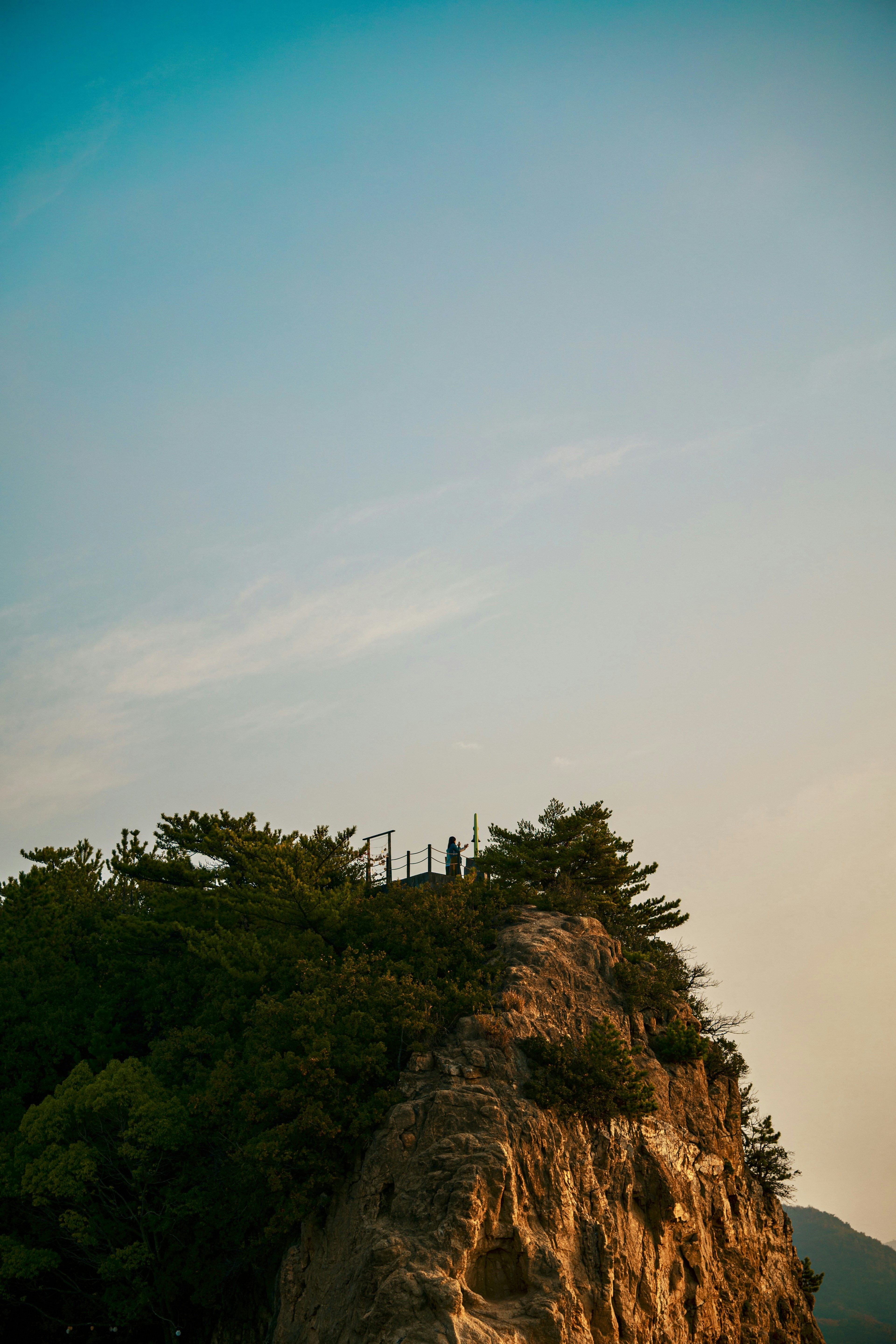 Landschaft einer Klippe mit grünen Bäumen und einem Farbverlauf im Himmel