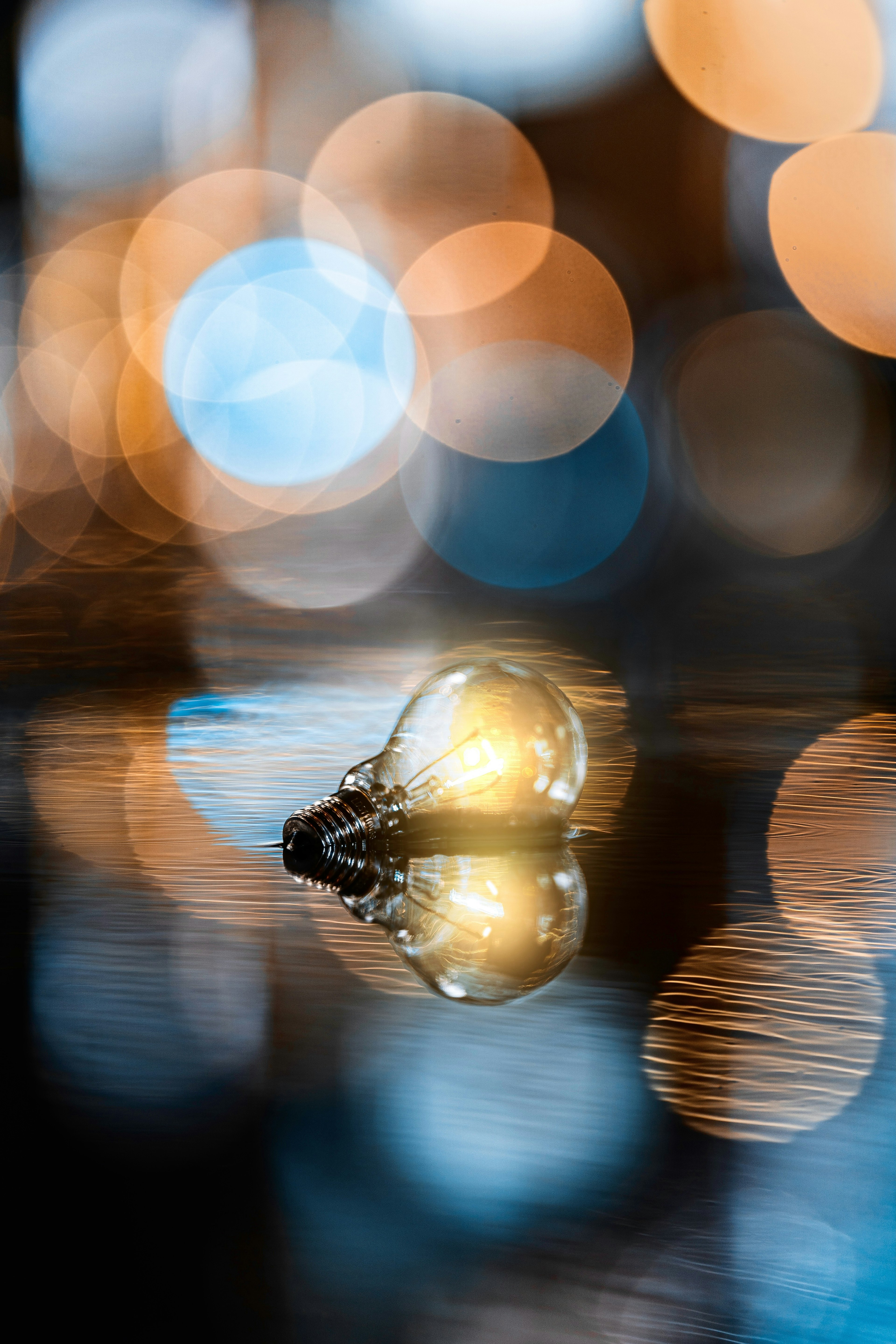 A light bulb reflecting on water with blurred bokeh lights in the background