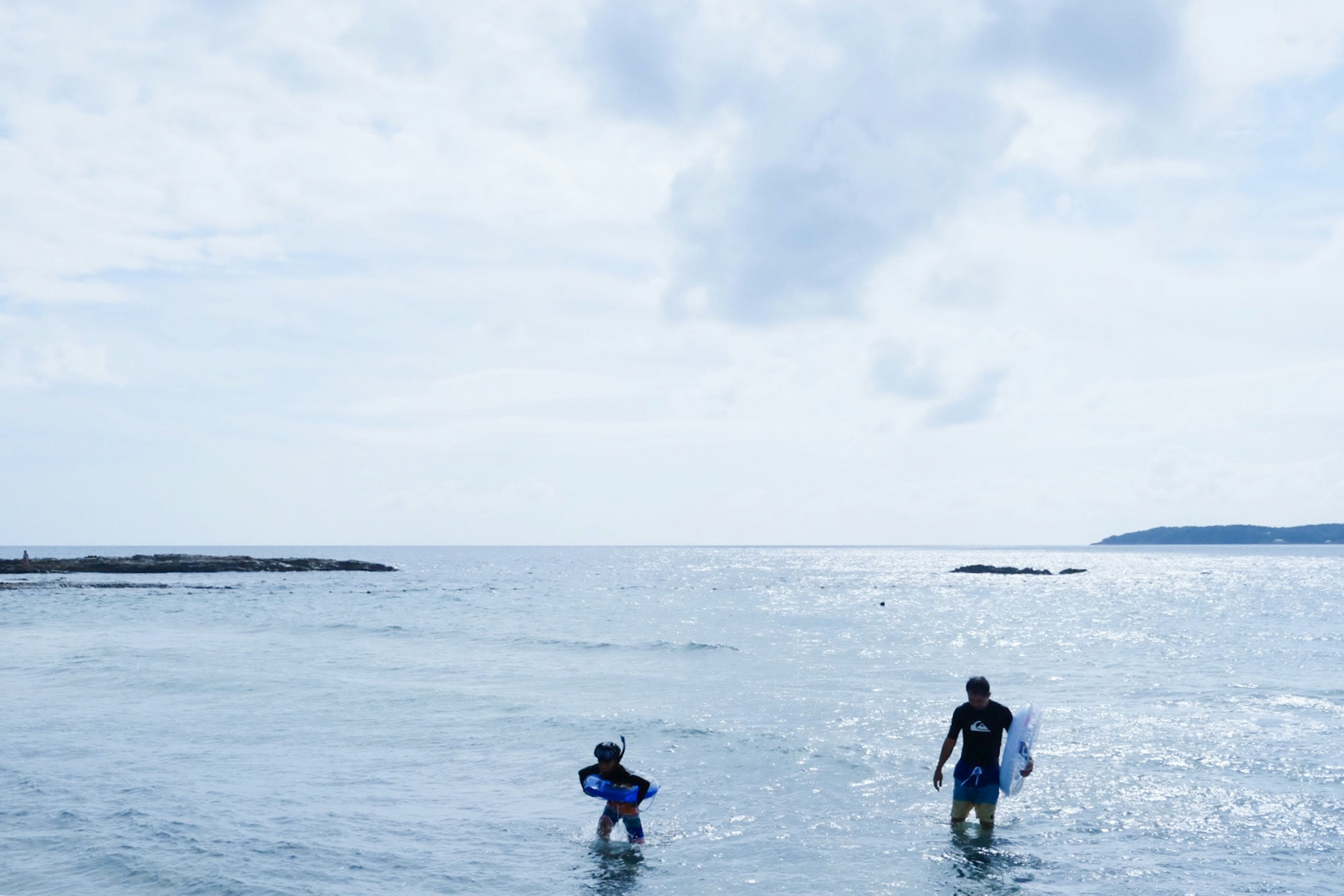 Silhouette eines Elternteils und eines Kindes, die im Ozean surfen