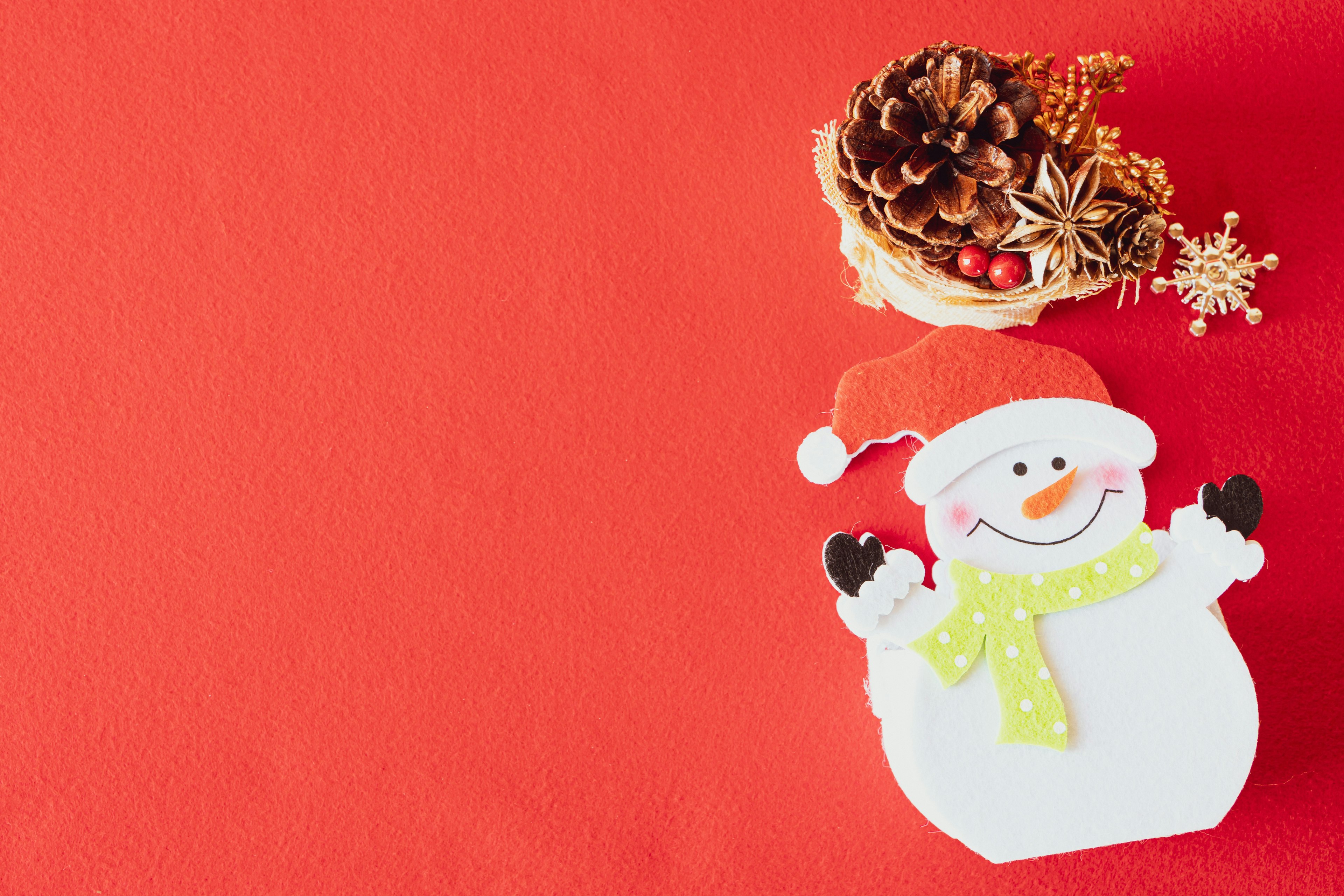 Snowman decoration with a red background and a pine cone arrangement