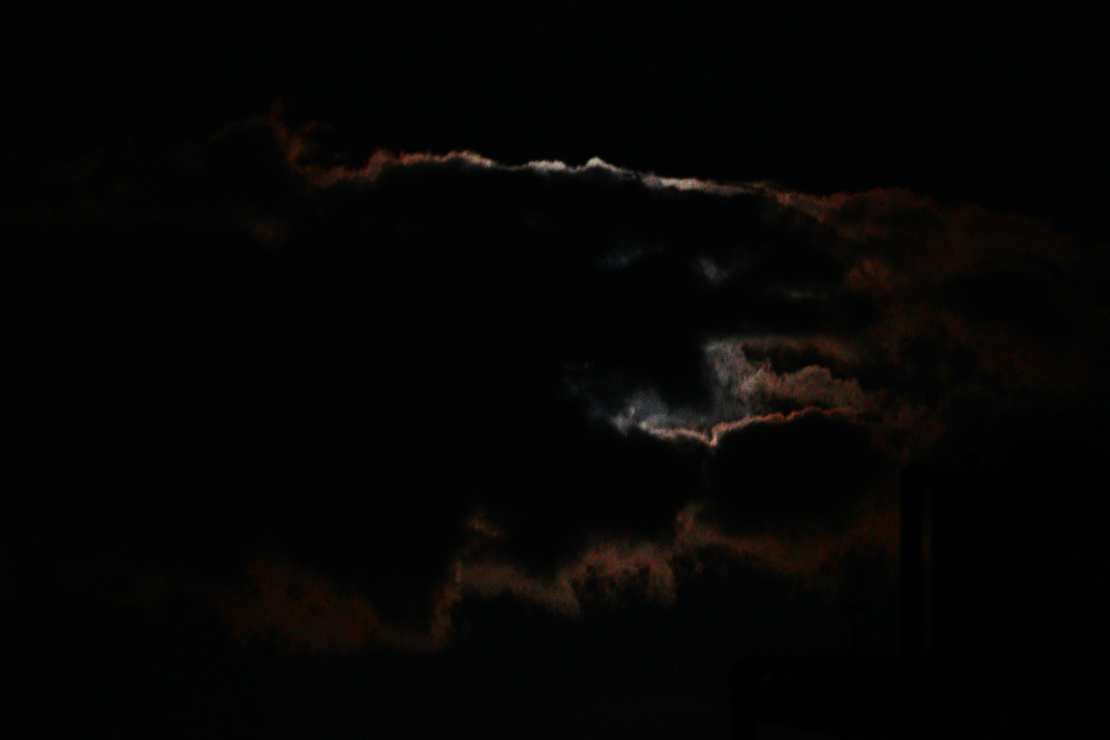 Nubes oscuras con un hueco que revela una tenue luz de luna