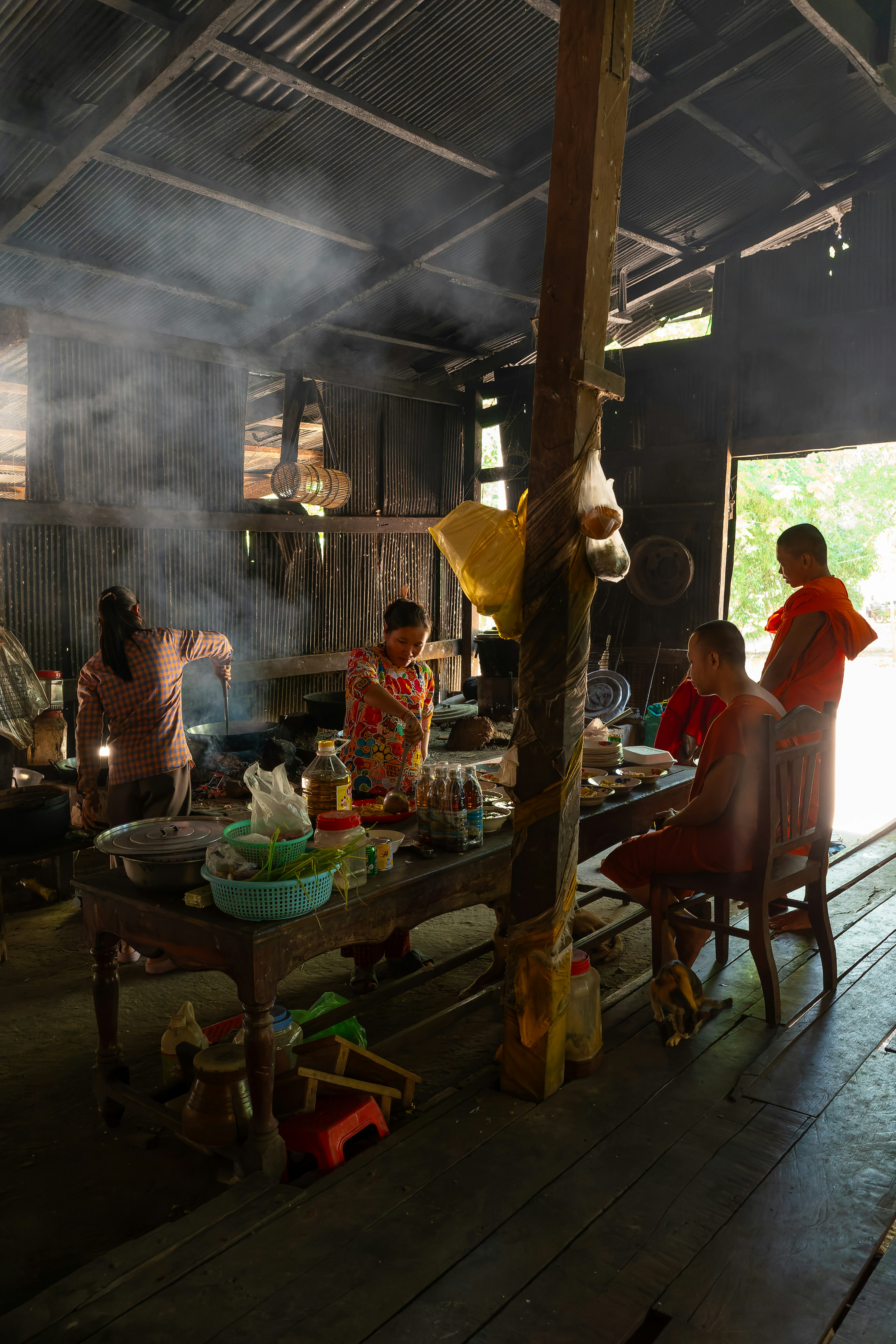 Orang-orang memasak di dapur rustic dengan asap dan dekorasi kayu