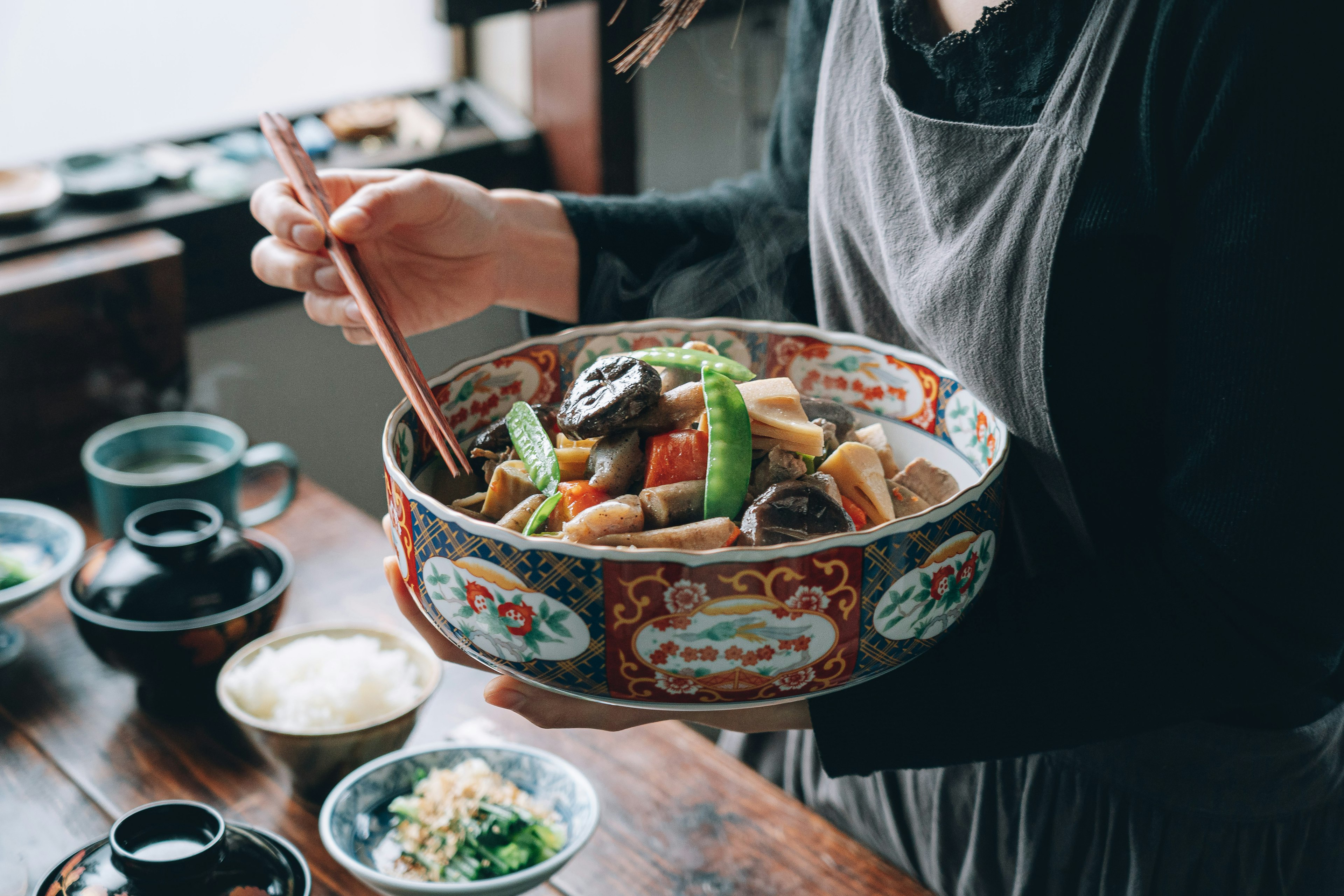 Eine wunderschöne japanische Schüssel mit buntem Gemüse und Gerichten, die von einer Person gehalten wird