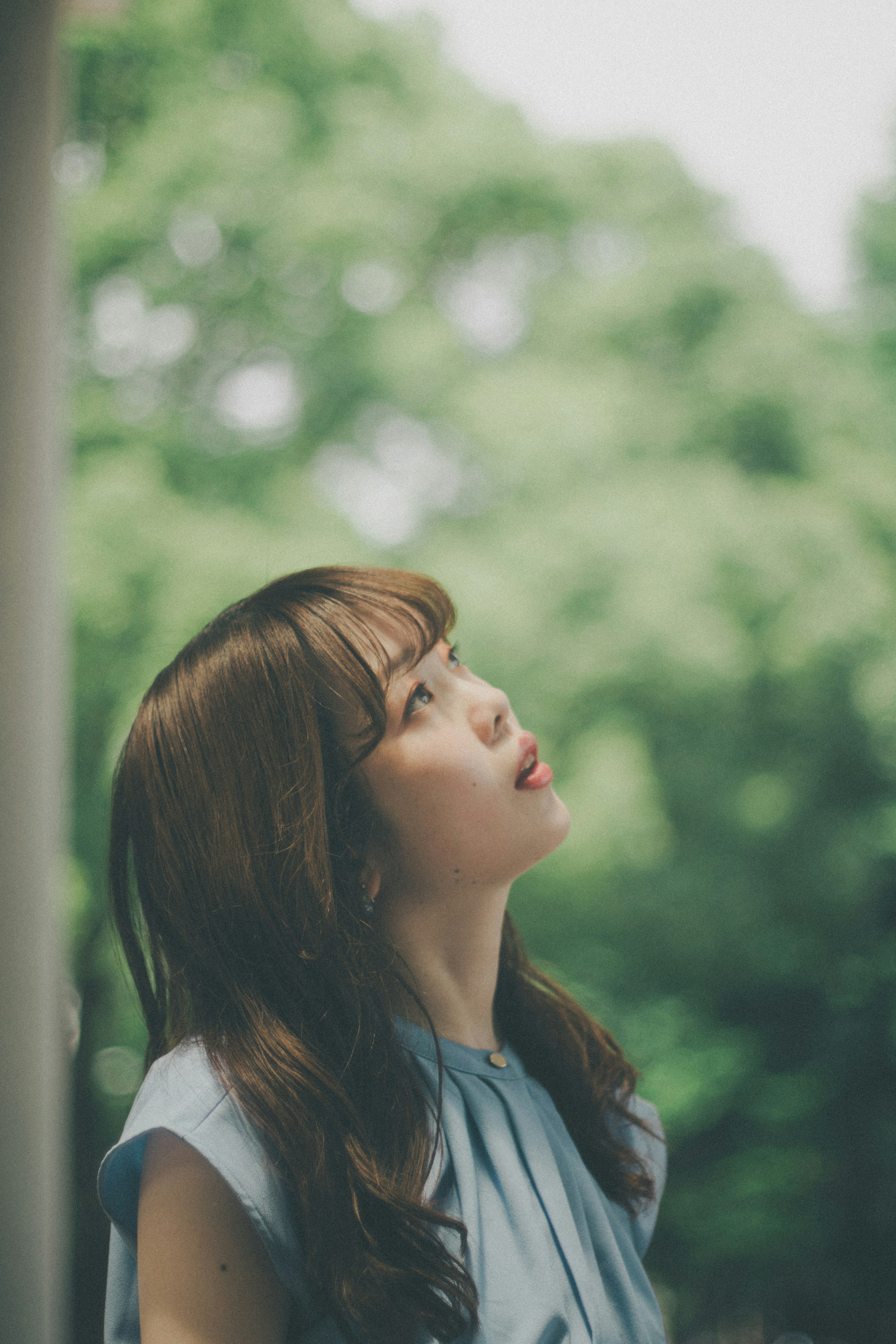 青いシャツを着た女性が空を見上げている写真