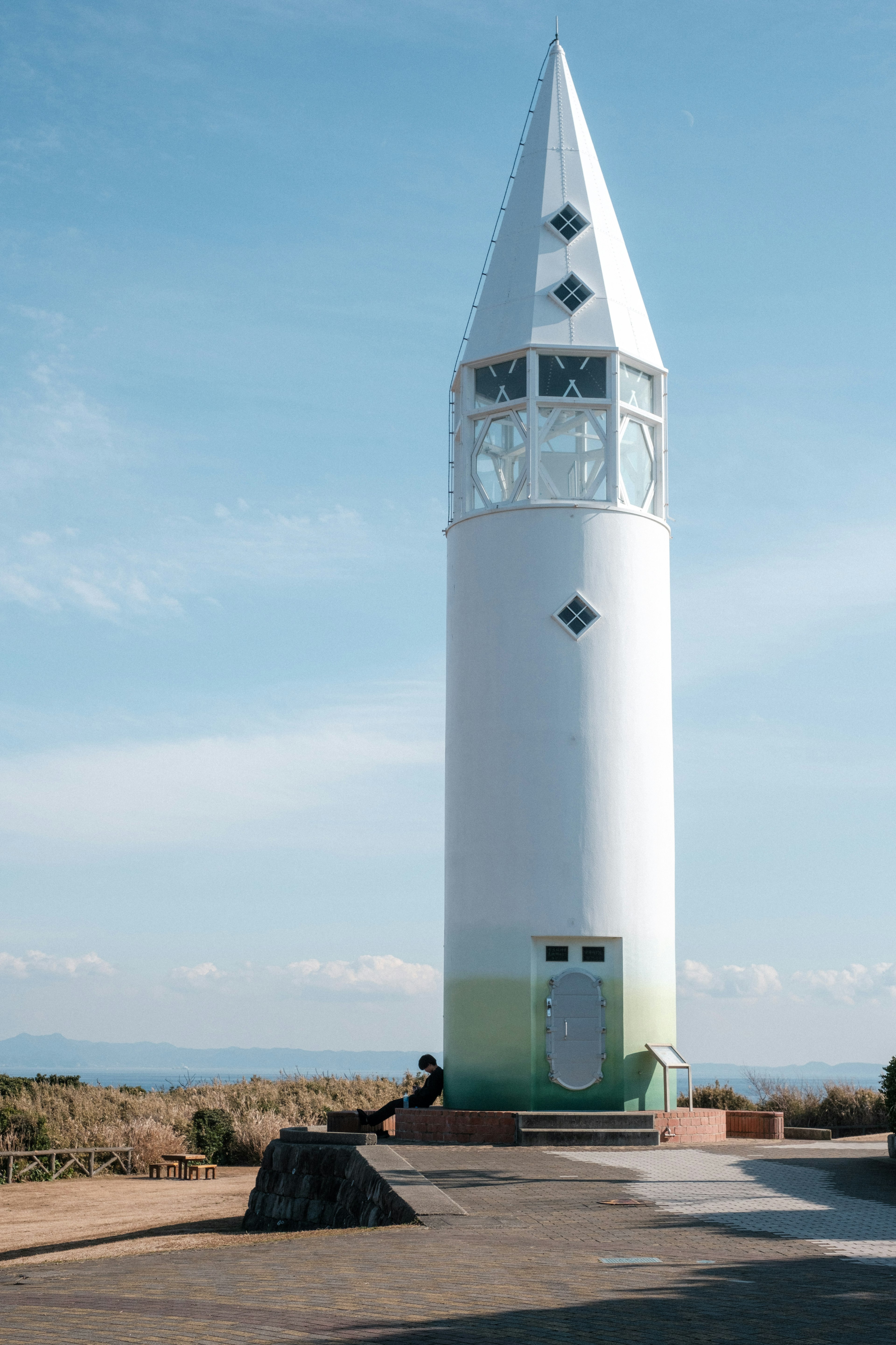 Torre bianca con tetto appuntito contro un cielo blu e terreni erbosi