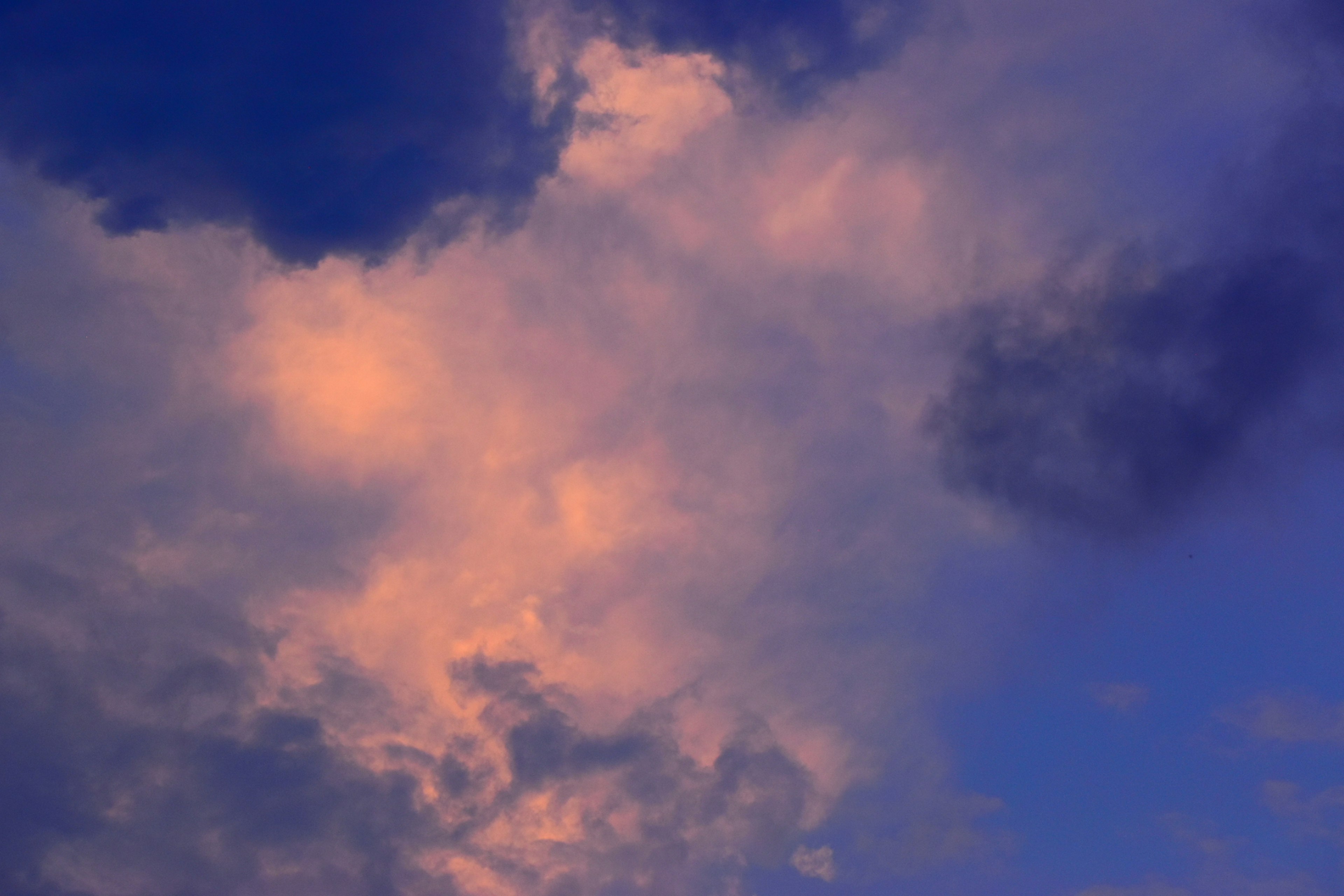 Soft clouds in a blue sky with hues of pink and purple