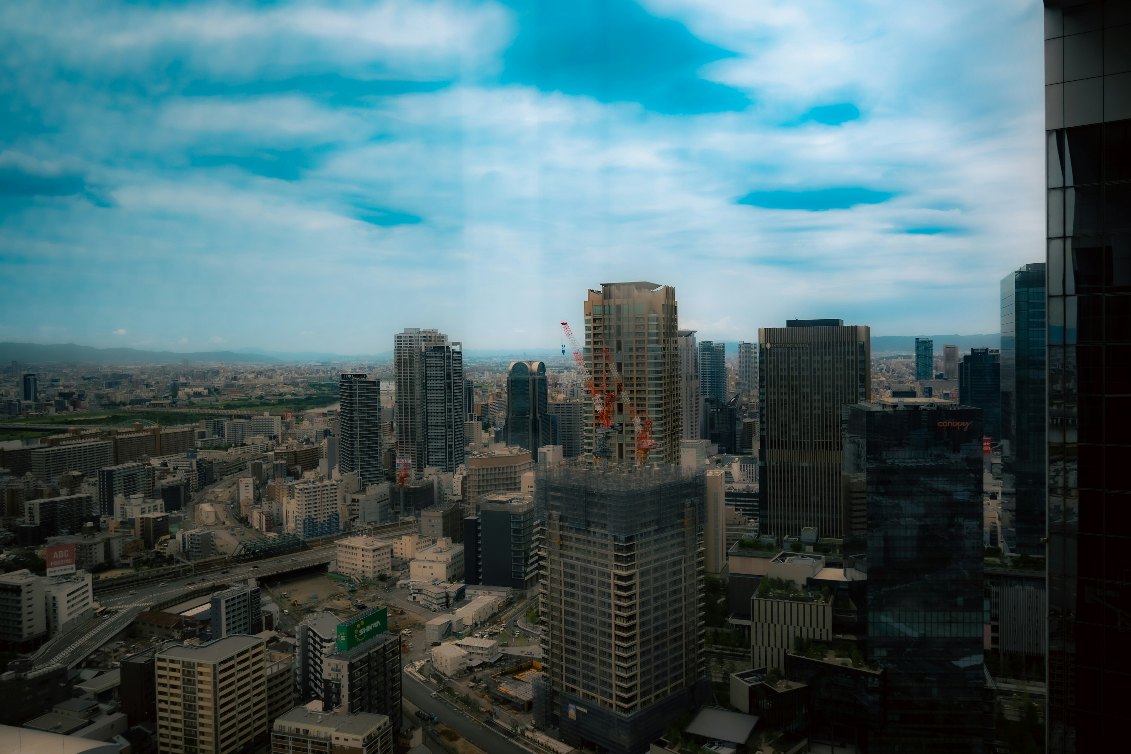 A view overlooking a city skyline with skyscrapers under a blue sky and clouds