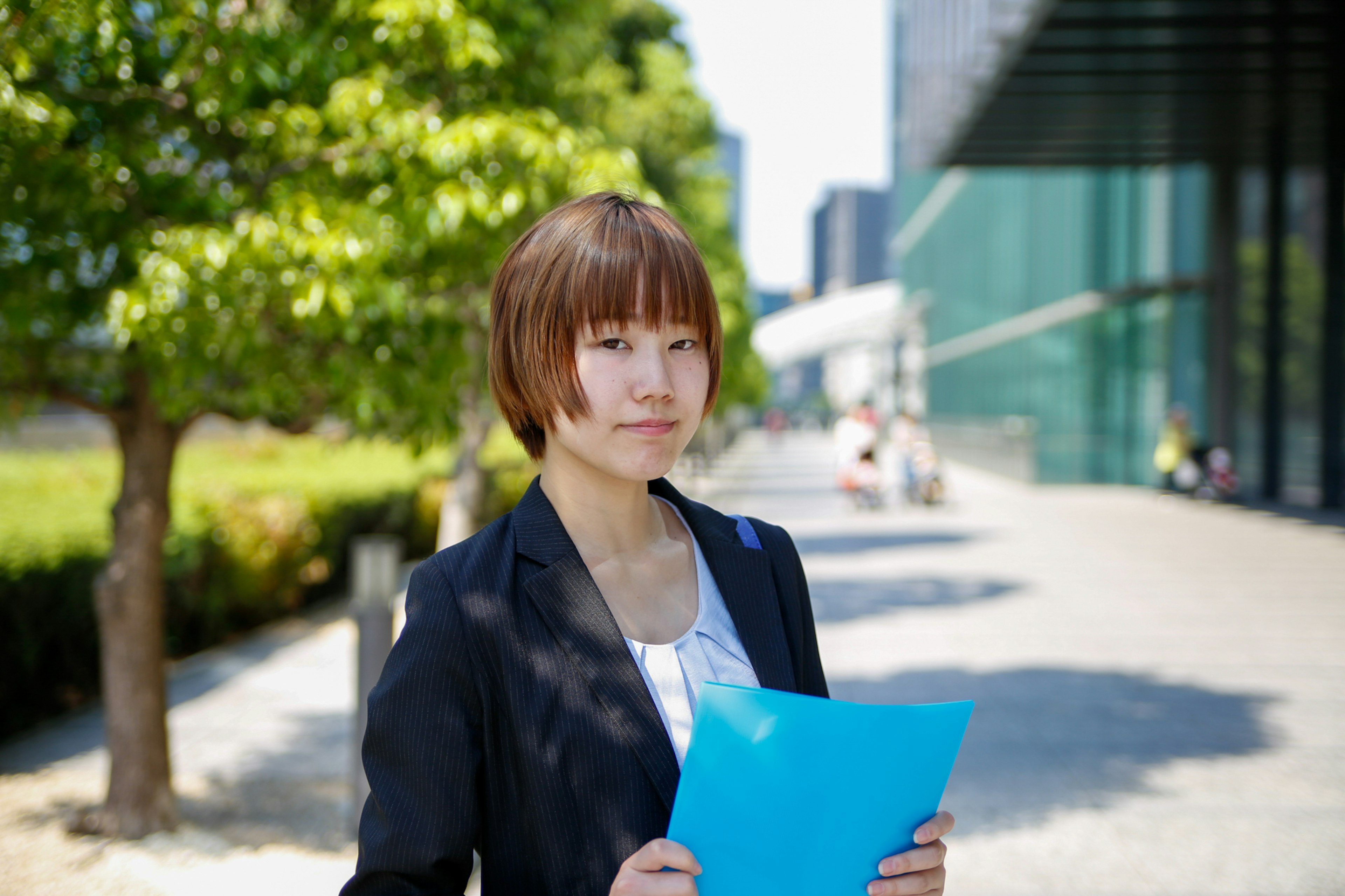 年轻女性手持蓝色文件夹站在公园