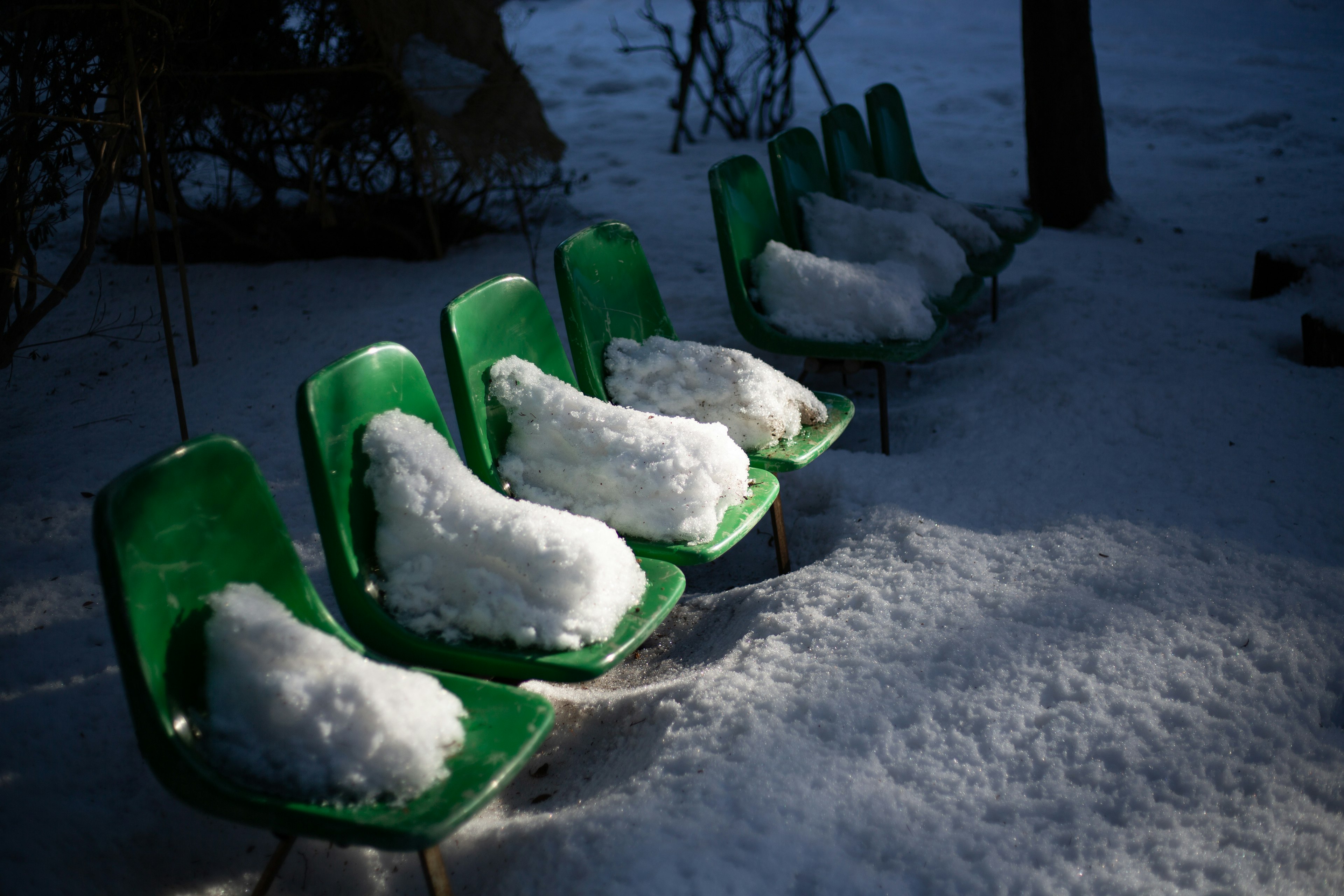 Fila de sillas verdes cubiertas de nieve en un entorno invernal