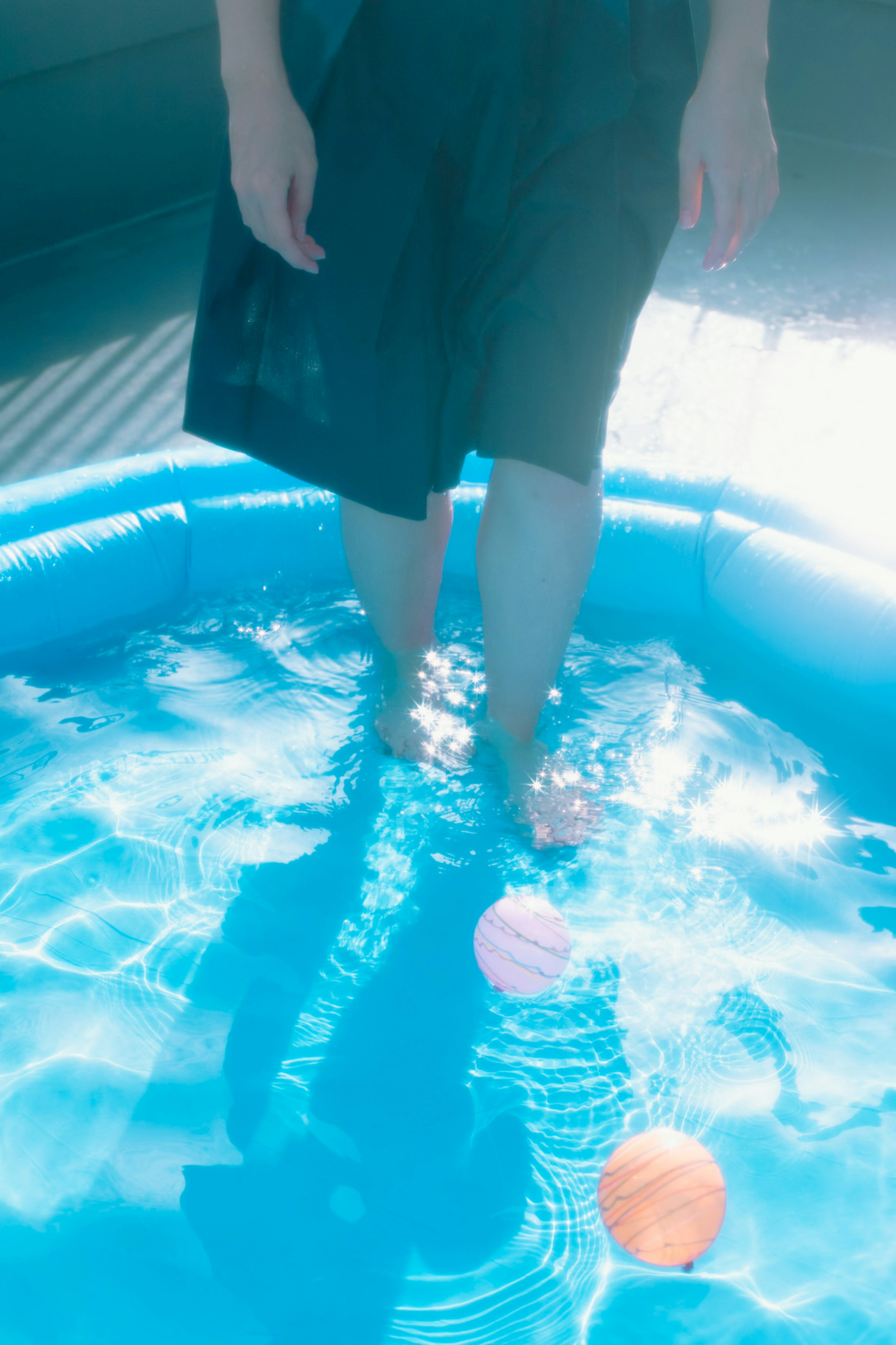 Pies de una persona en una piscina azul con pelotas de colores