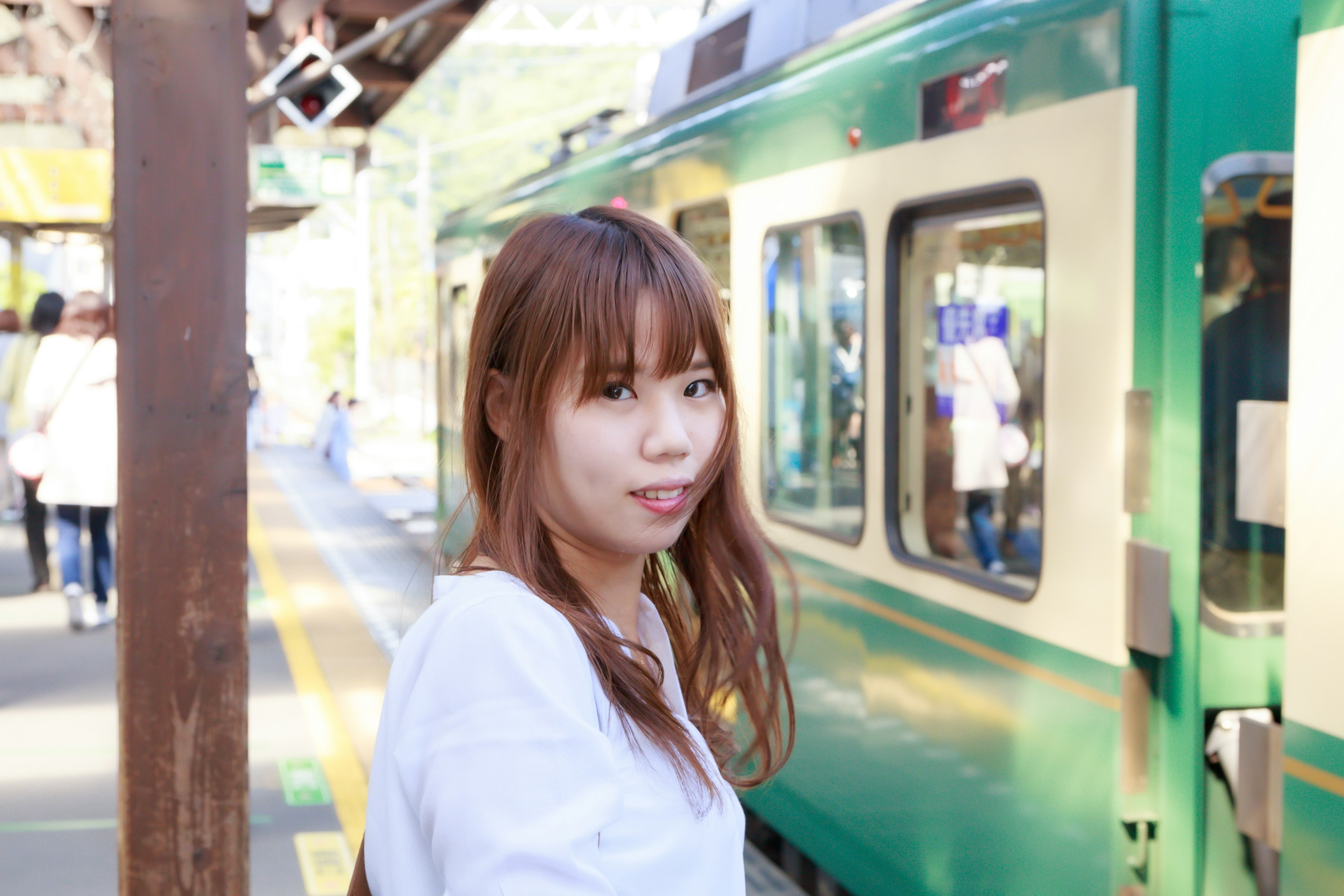 Mujer sonriendo en la estación con un tren verde